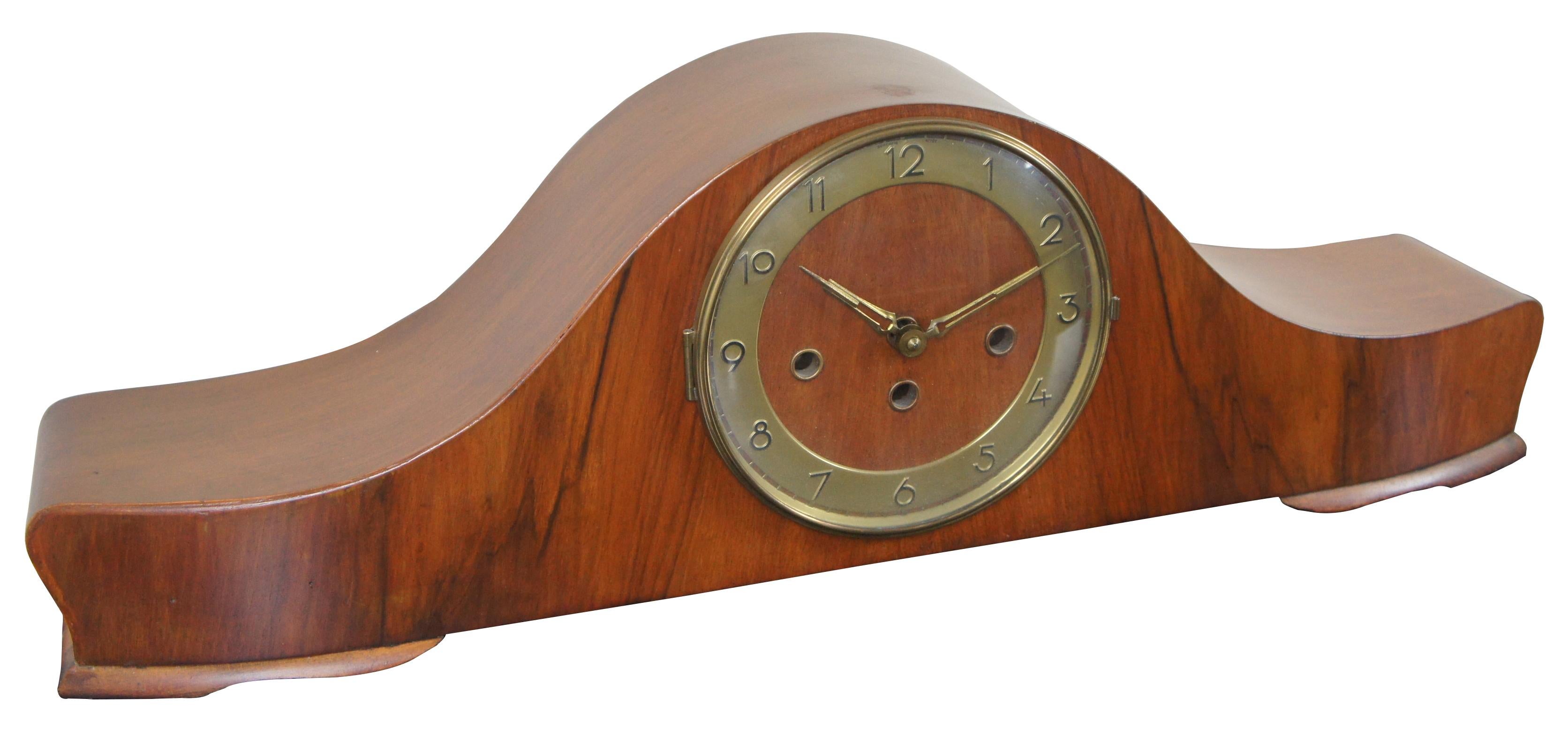 Antique Art Deco style, key wound, chiming mantel clock with a wooden oxbow/yoke shaped case and brass numbers. Measures: 26