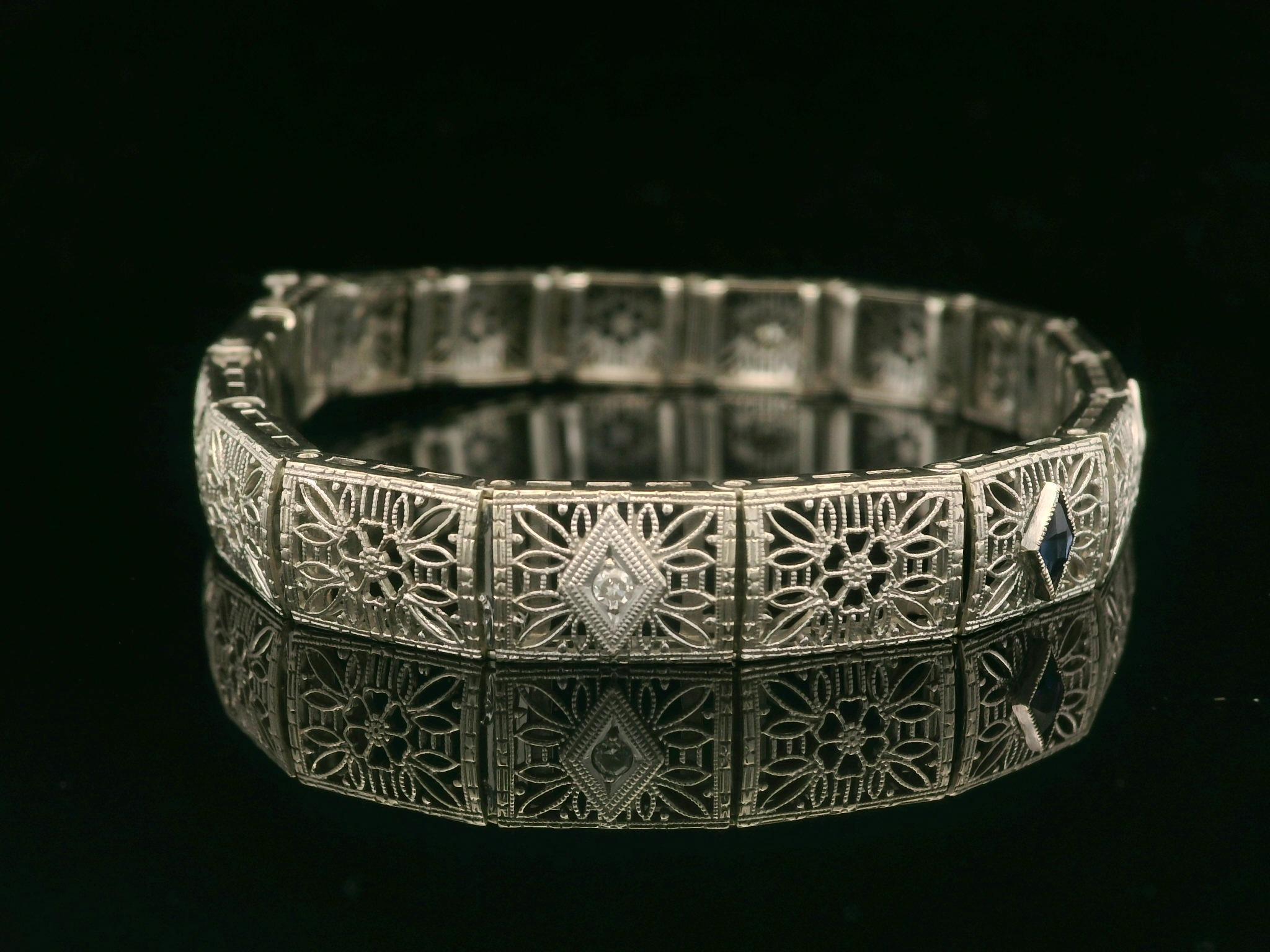 –Stone(s)–
(3) Natural Genuine Diamond - Old Single Cut - Pave Set - Nice White Color - 0.06ctw (approx.)
(2) Synthetic Sapphire - Lozenge Cut - Milgrain Bezel Set - Deep Blue Color 

Material: 14k White Gold
Weight: 14 Grams
Type: Floral Filigree