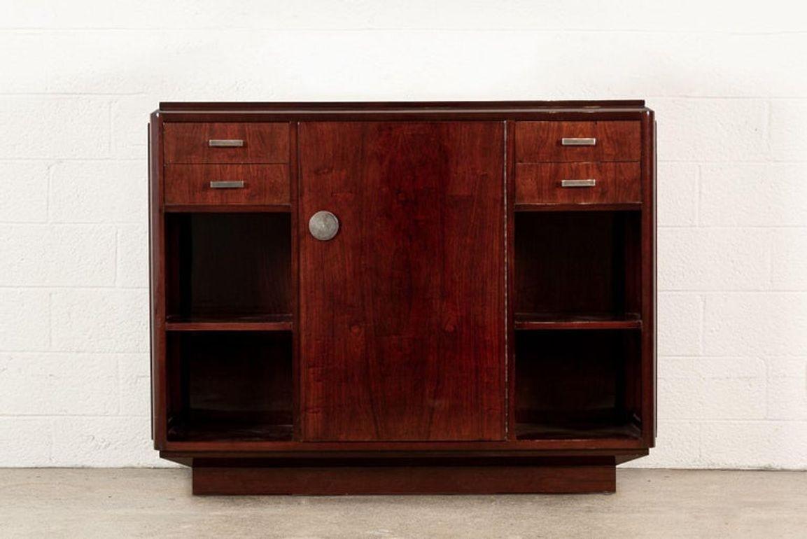 This exceptional antique French Art Deco walnut wood bar cabinet or sideboard buffet credenza is circa 1940. The cabinet is expertly hand-crafted from walnut wood in deep, rich mahogany tones with a lacquered finish. The distinctive, streamlined