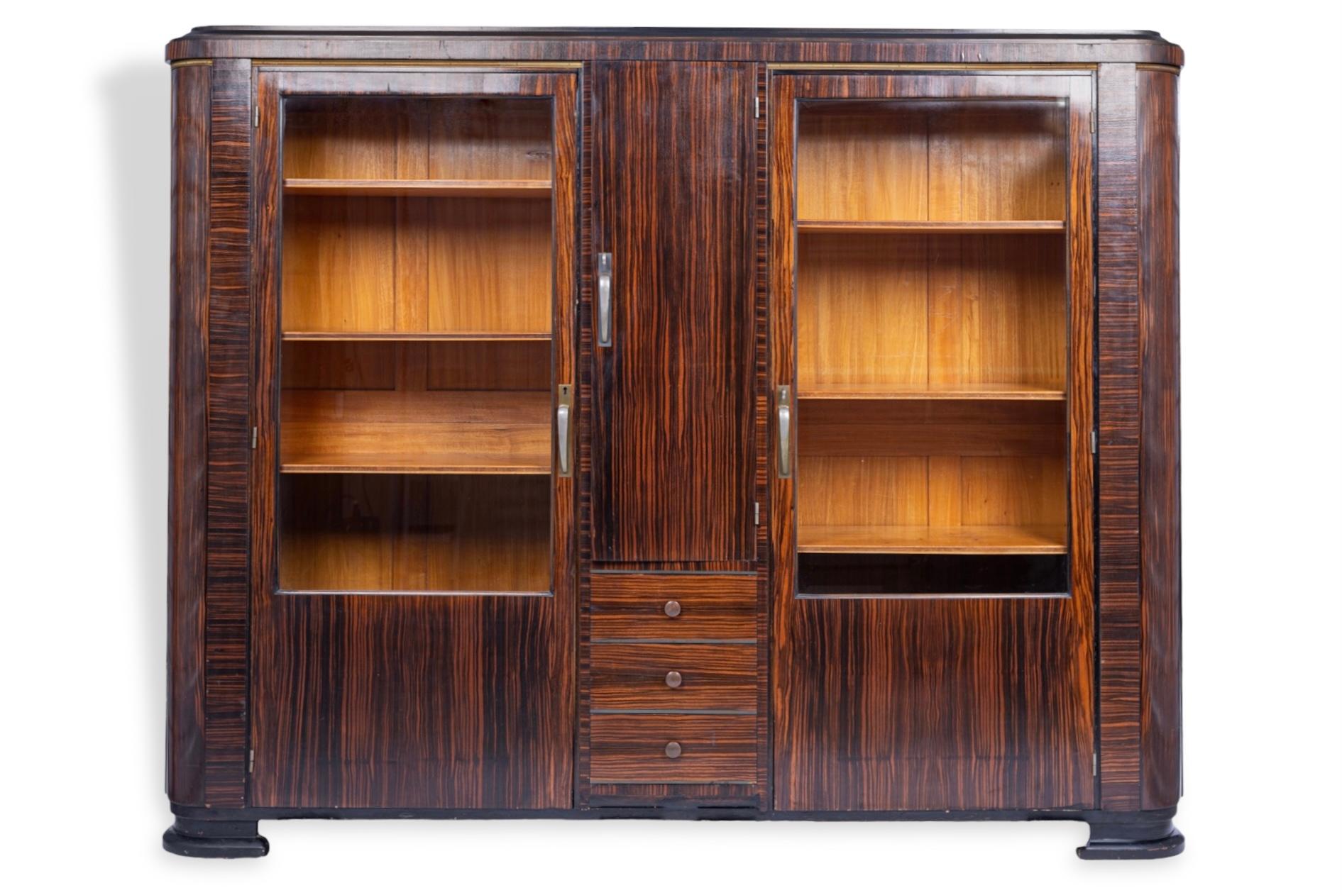 This truly exquisite antique Art Deco zebrawood and glass display cabinet or bar cabinet is circa 1930. It is expertly handcrafted from solid wood and zebrawood veneer with rich, deep browns and gorgeous zebra-striped grain patterning. This large,