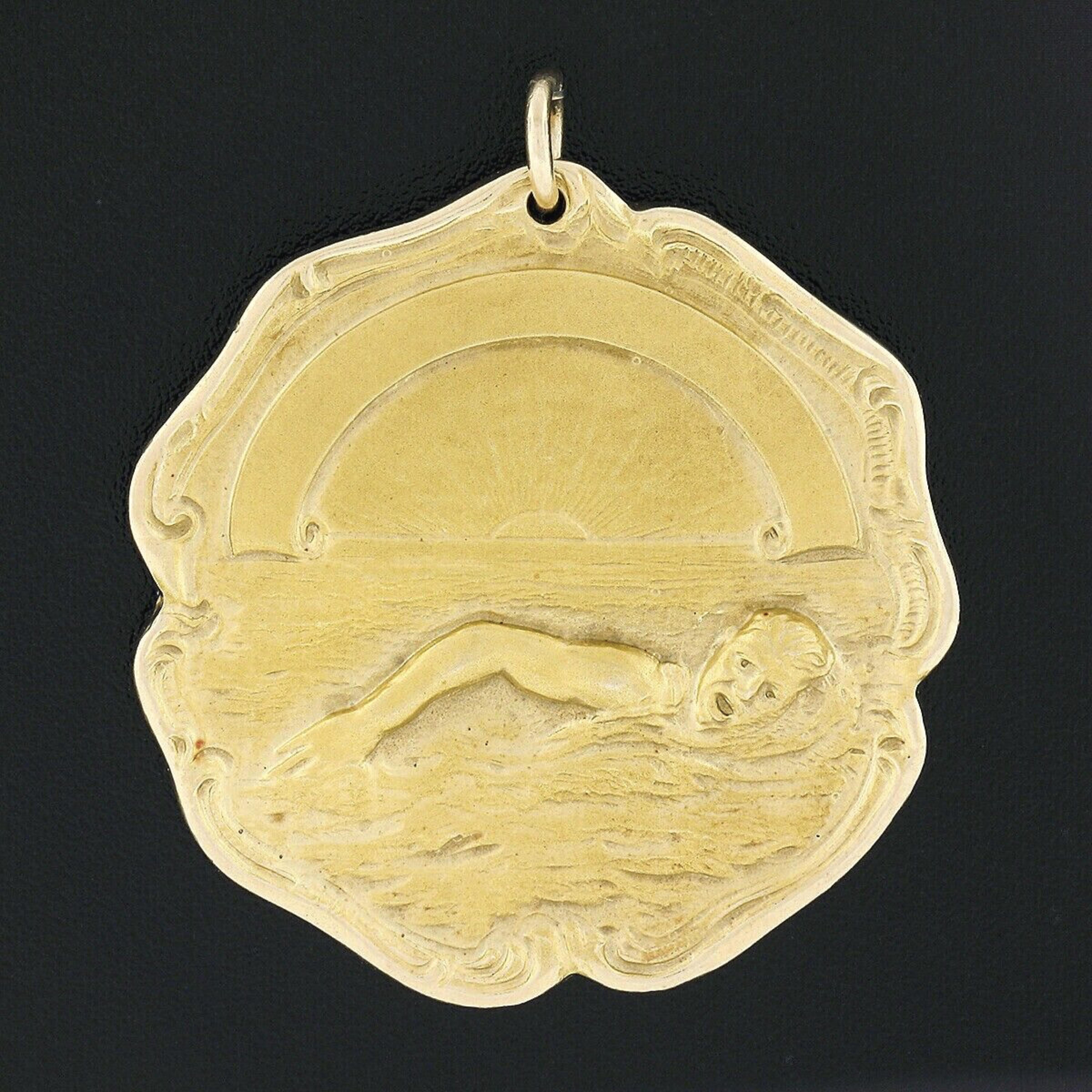 This magnificent and very well made antique medal medallion pendant is crafted in solid 14k yellow gold. It features a highly detailed scene of a man swimming at its front side with nice matte finish throughout. The back of the medal is neatly