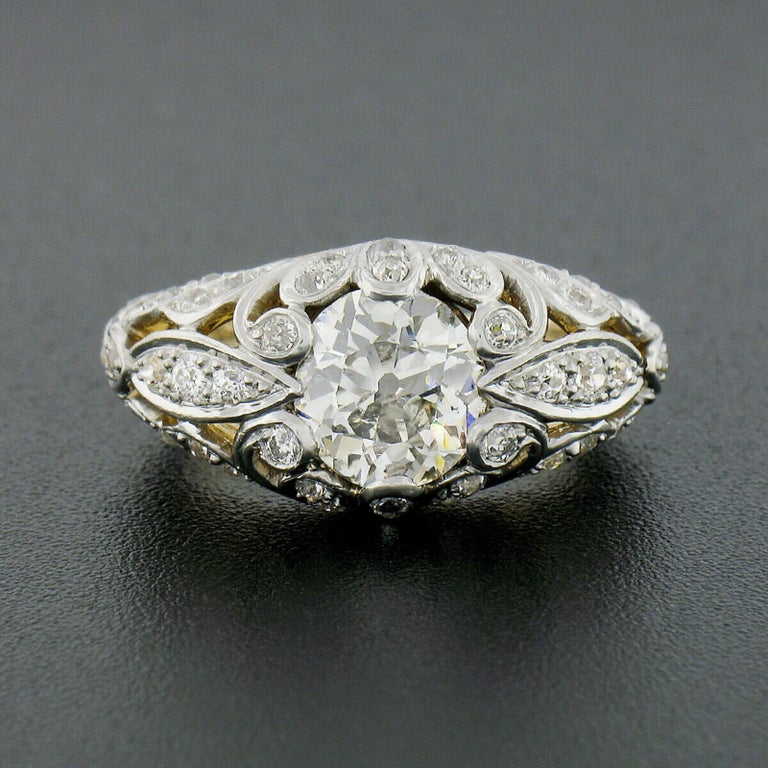 This exceptional antique band ring was well-crafted from solid 18k yellow and white gold during the art nouveau period. It displays elegant and domed pierced floral work throughout and is completely covered in gorgeous old cut diamonds. The center