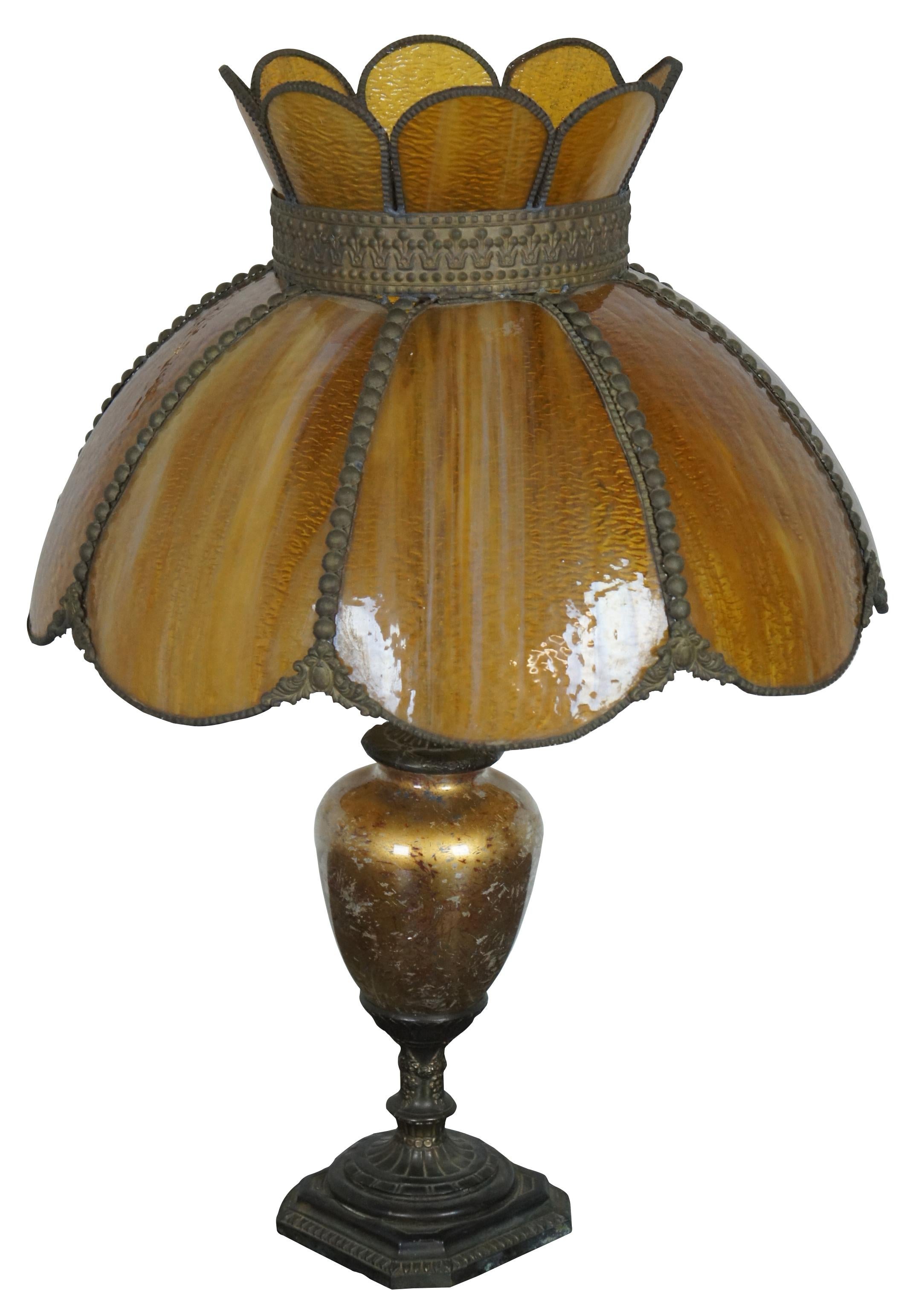 Antique slag glass table lamp. Features a golden reverse painted urn body and flower shaped, Tiffany style amber slag glass shade.

Measures: 5.5” x 23.25” / shade - 18” x 11.25” / height with shade – 25.25” (diameter x height).