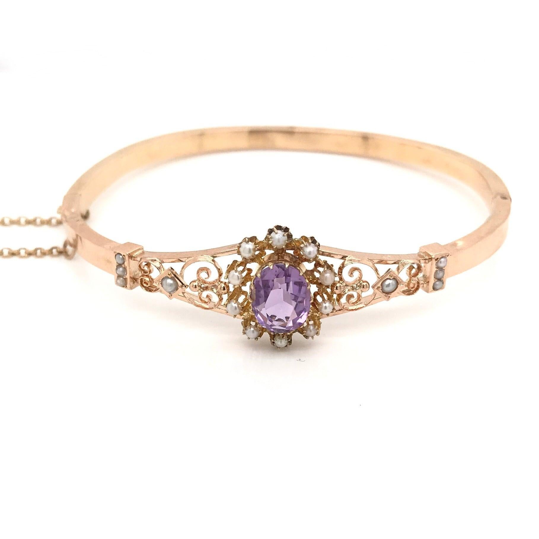 This gorgeous antique piece was crafted sometime during the Art Nouveau design period (1890-1915). The bangle is 14K gold and features a center Amethyst with a softer lilac hue and saturation. The center Amethyst is surrounded by a halo of 10