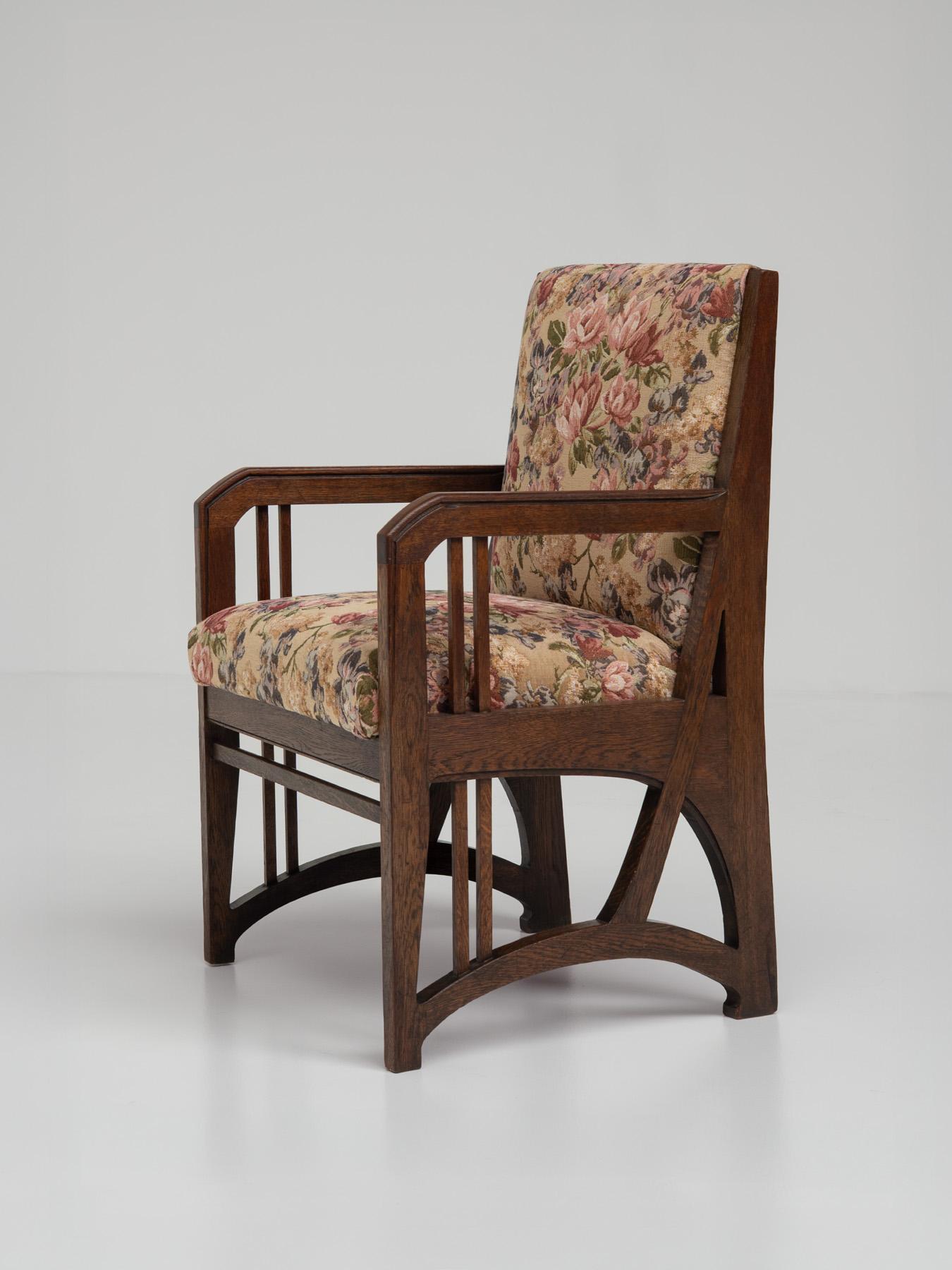 This elegant armchair, crafted around 1900–1910, is a true masterpiece of early 20th-century craftsmanship, blending the clean geometry of the Arts and Crafts movement with the organic lines of Art Nouveau, the French and Belgian counterpart to the