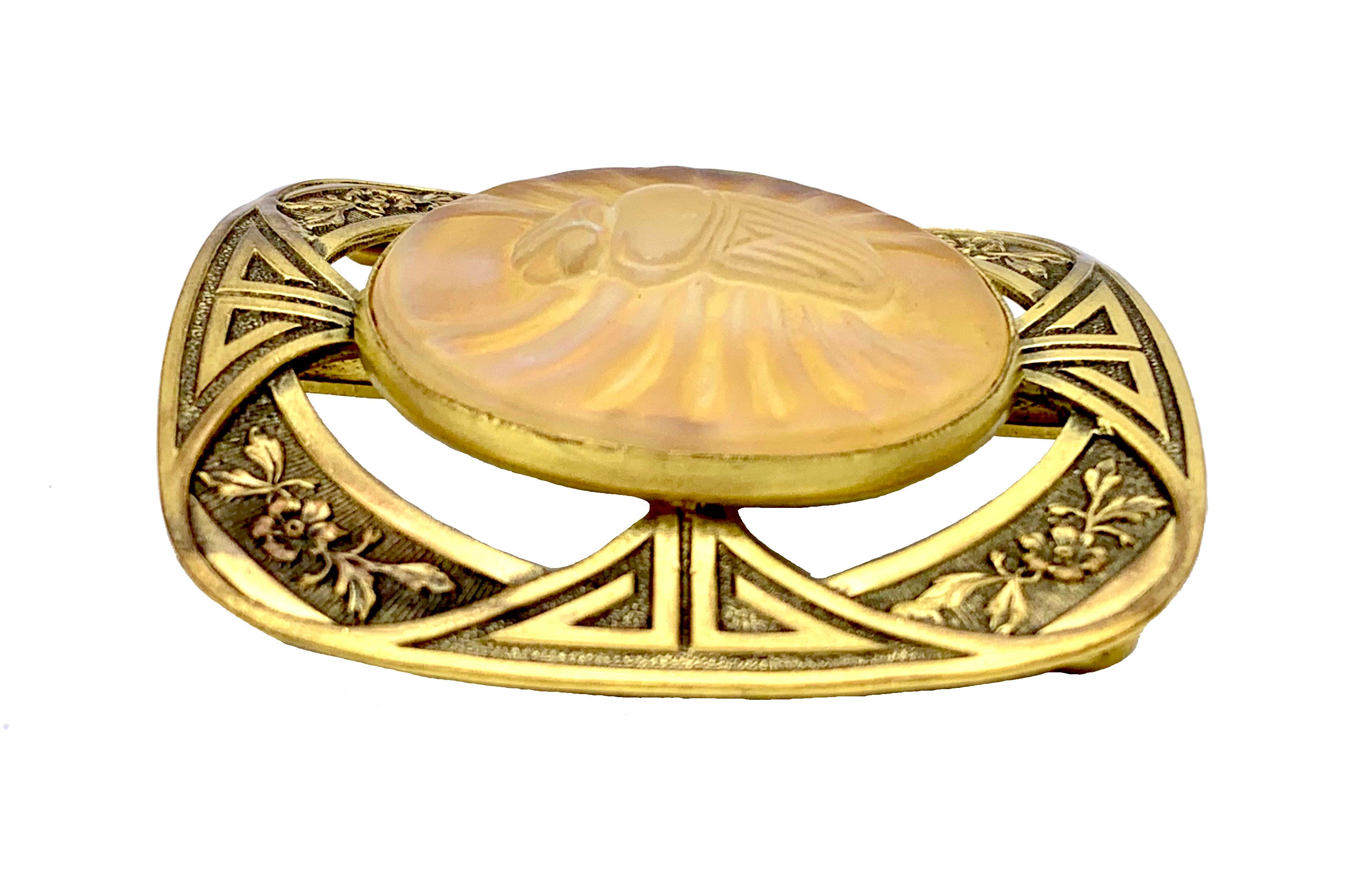 This beautiful round piece of gold coloured pâte de verre depicting a winged scarab was created around 1900, probably in Nancy, France.  It is mounted in a square belt buckle with rounded corners, a strong piece of Art Nouveau design.
It has been