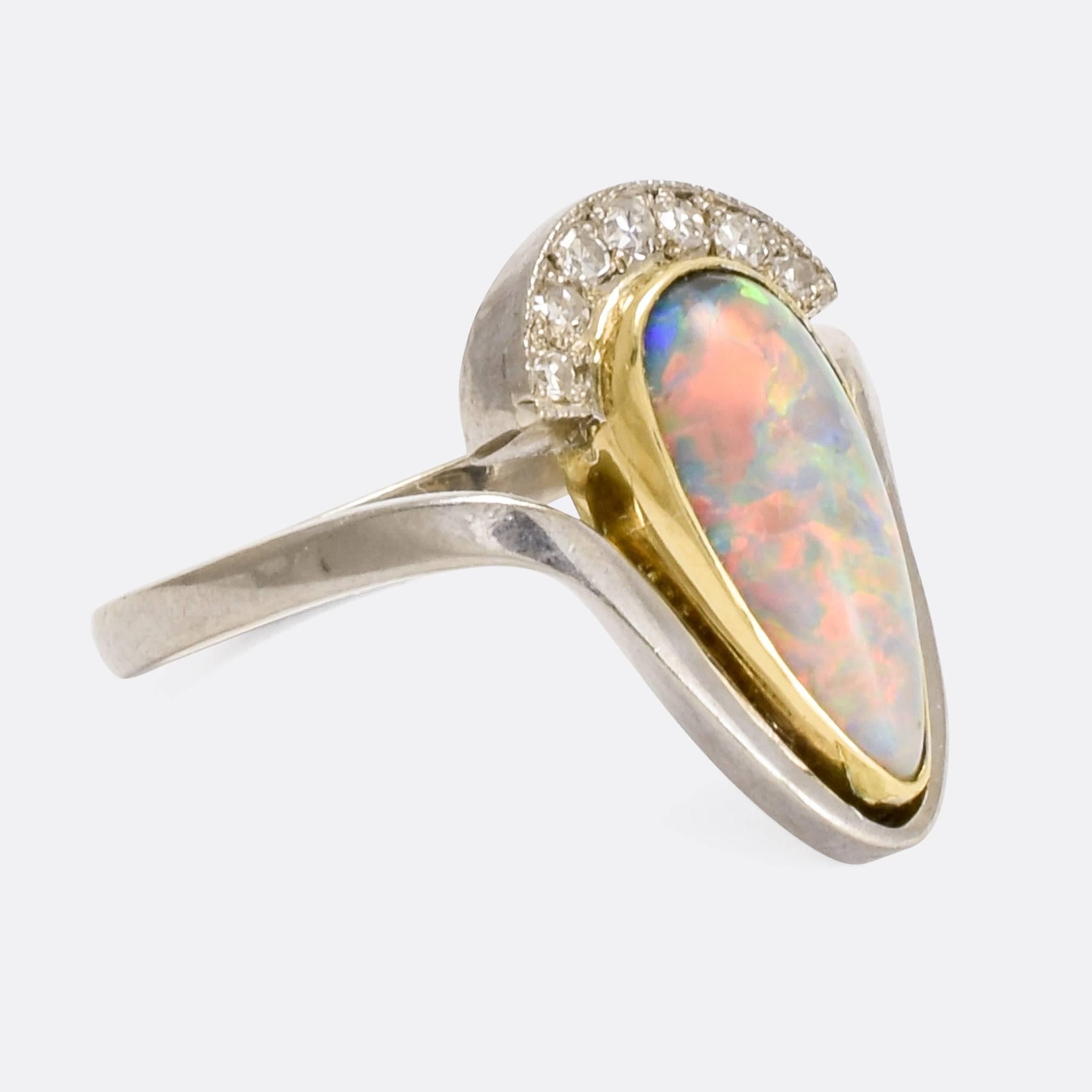 A striking Art Nouveau ring set with a pear-shaped Black Opal with a crown of white diamonds. It was made in England in the early 20th Century, circa 1910, modelled in two-tone 18 karat gold with fine millegrain detailing around the diamonds.