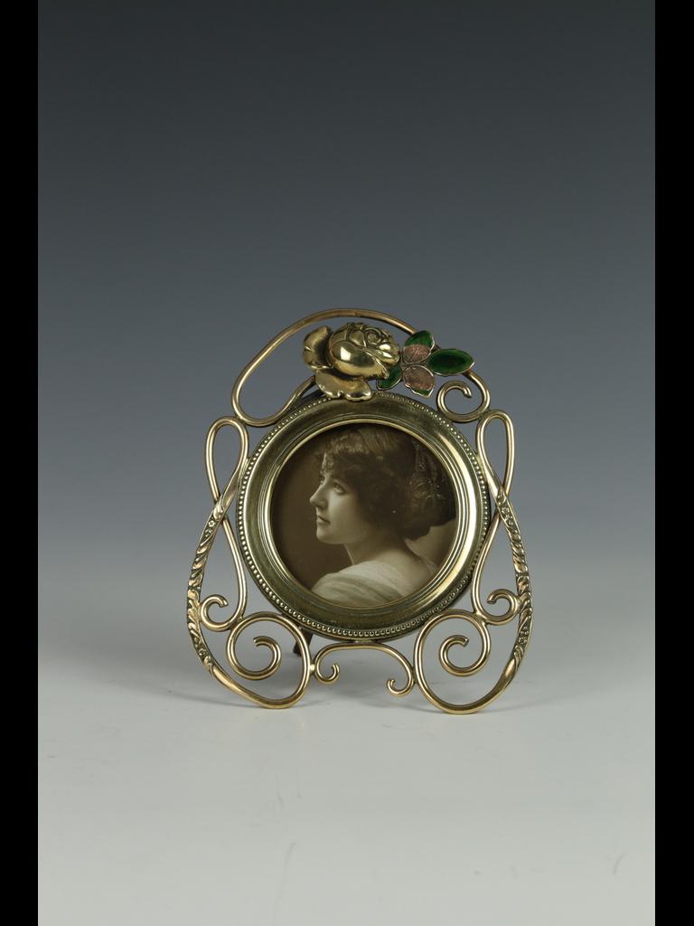 Cadre photo ancien en laiton Art nouveau avec motif de rose et d'émail

Ce délicat et magnifique cadre photo antique en laiton Art Nouveau présente une petite forme circulaire d'un diamètre de 3 pouces. Le cadre est orné de volutes complexes en
