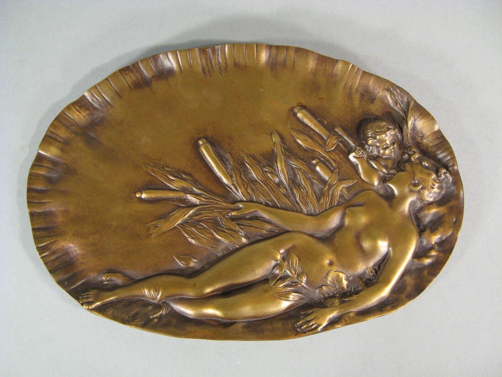 This exquisite Art Nouveau decorative tray, crafted in bronze, features a captivating bas-relief of a Naiad and a mischievous Cupid attempting to place a reed in the mouth of the reclining beauty. Signed on the lower left by French sculptor Emile