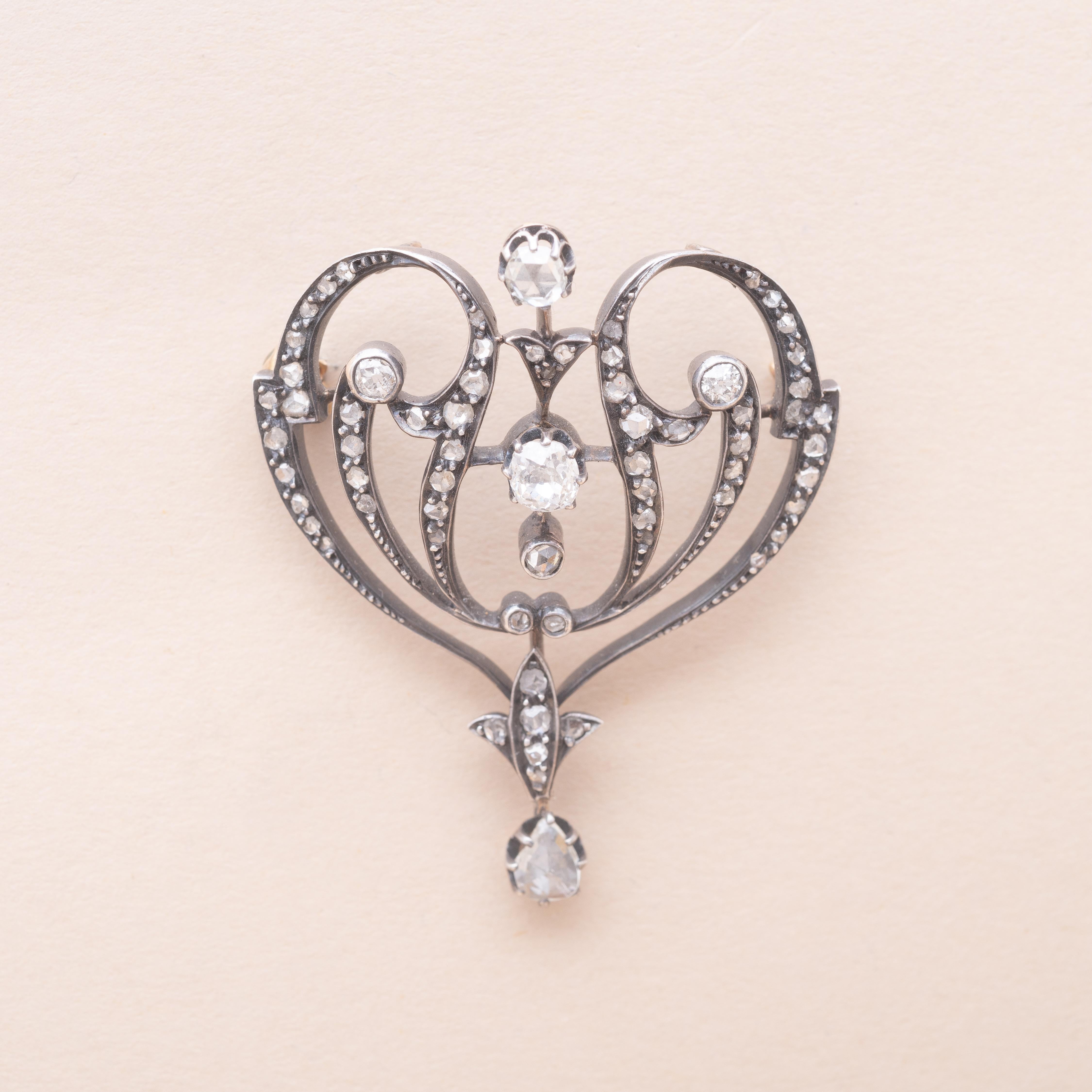 Volute Art Nouveau silver and 18K gold pendant brooch. Old-cut and rose-cut diamonds. Small old-cut diamond tassel. 

1900s Art Nouveau
Total estimated diamond weight : 0.50 carat 
Two hoops on the back allow to wear it as a pendant
Dimensions : 43