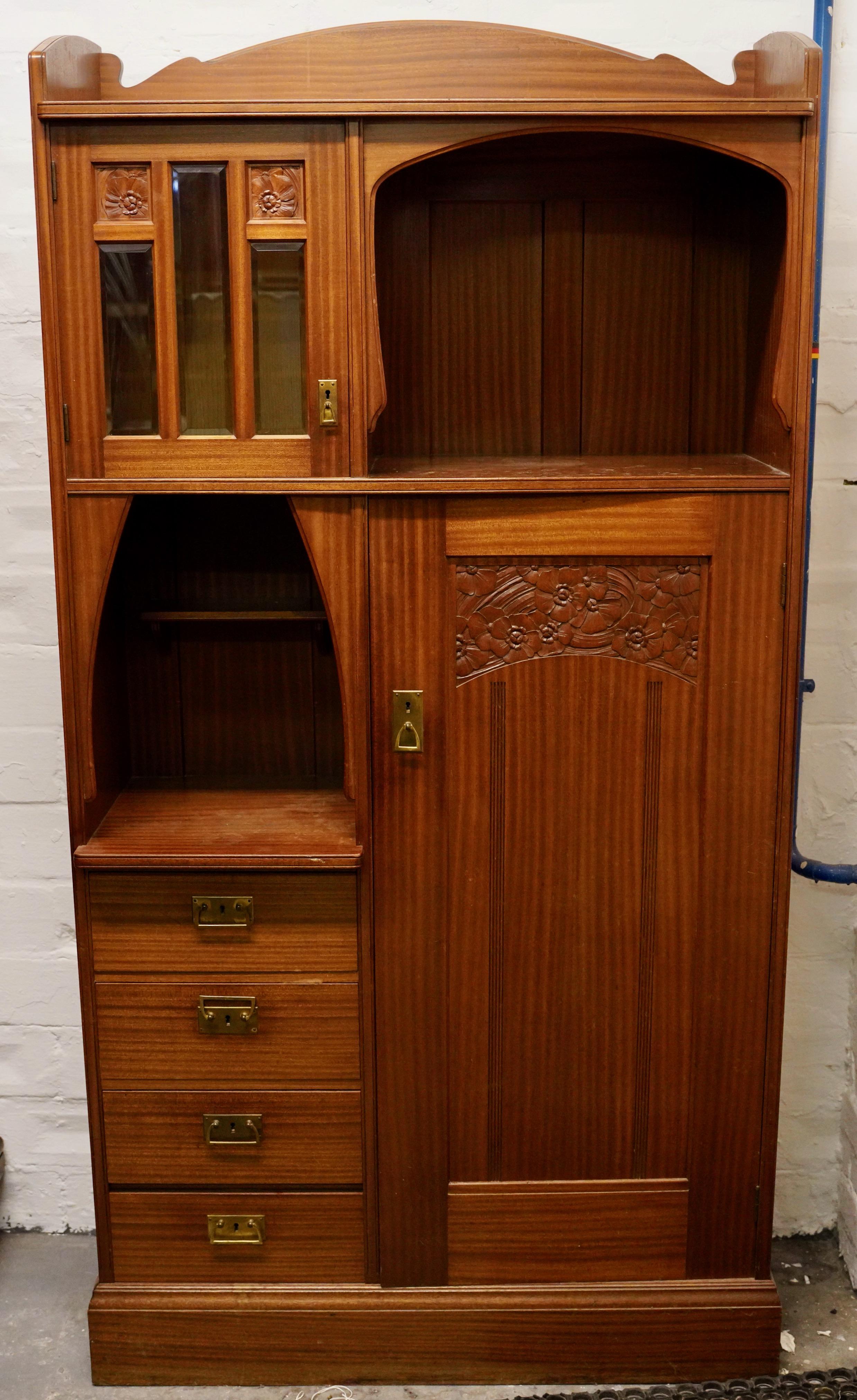 This impressive antique cabinet comes from the Art Nouveau era, around 1900. The cabinet impresses with its artistic decorations and the typical organic design language of this style. With a height of 198 cm, a width of 100 cm and a depth of 42 cm,