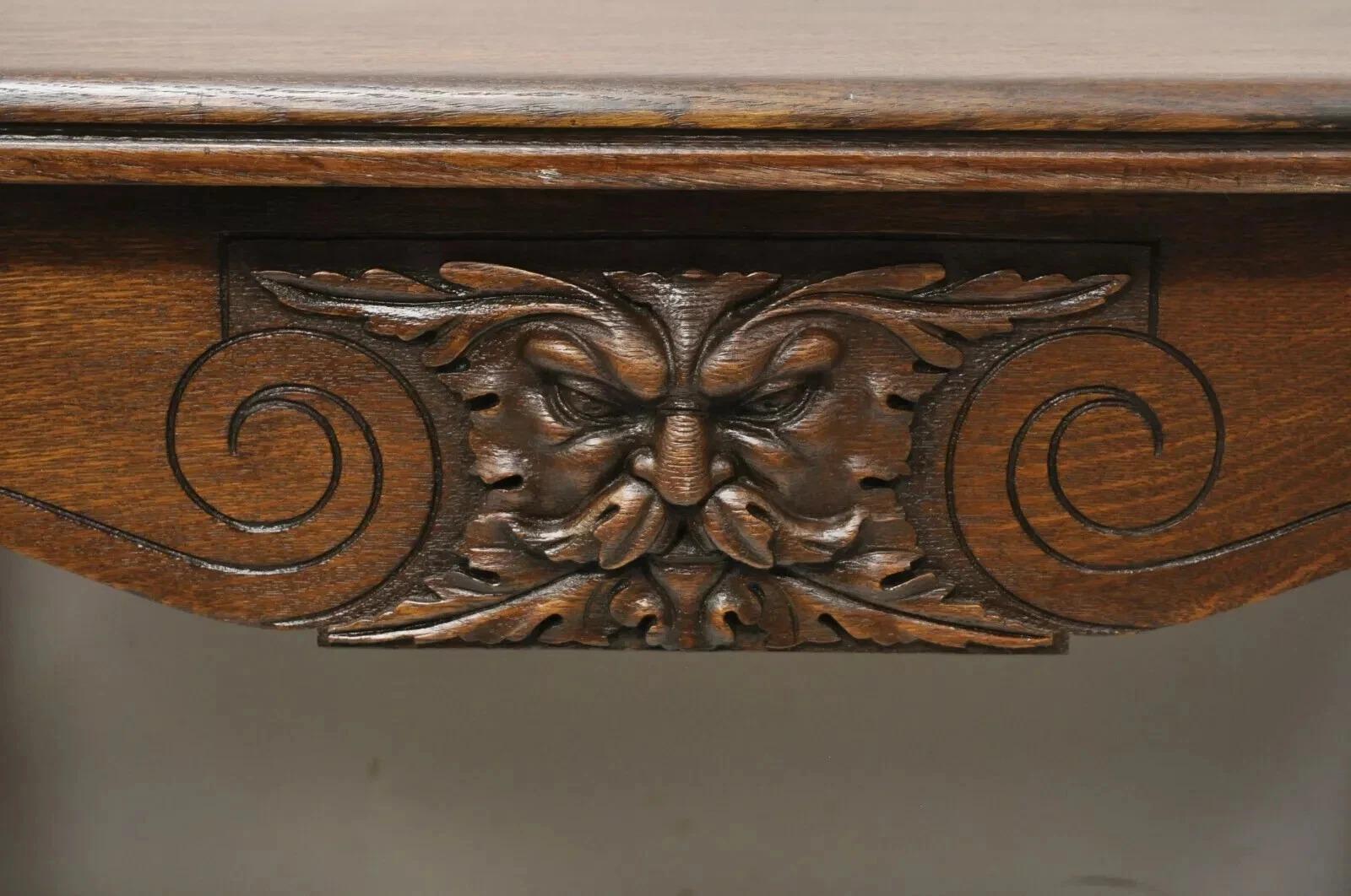 Antico tavolo da biblioteca in quercia intagliata Art Carved Northwind con un grande cassetto a coda di rondine. L'articolo presenta facce di Wood Wood intagliate sul davanti e sul retro, supporti angolari in ottone, struttura in legno massiccio di