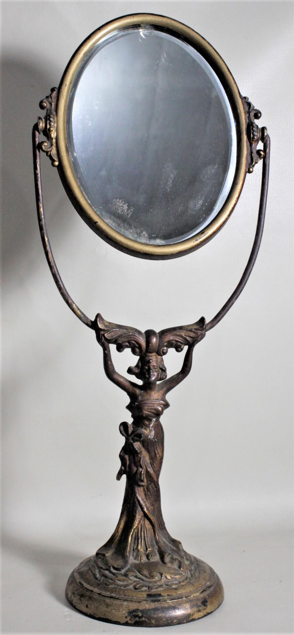 This antique cast figural ladies pedestal dresser mirror is unsigned, but presumed to have been made in France in circa 1890 in the period Art Nouveau style. The base of the mirror is a detailed cast metal woman in a flowing dress with a bronze