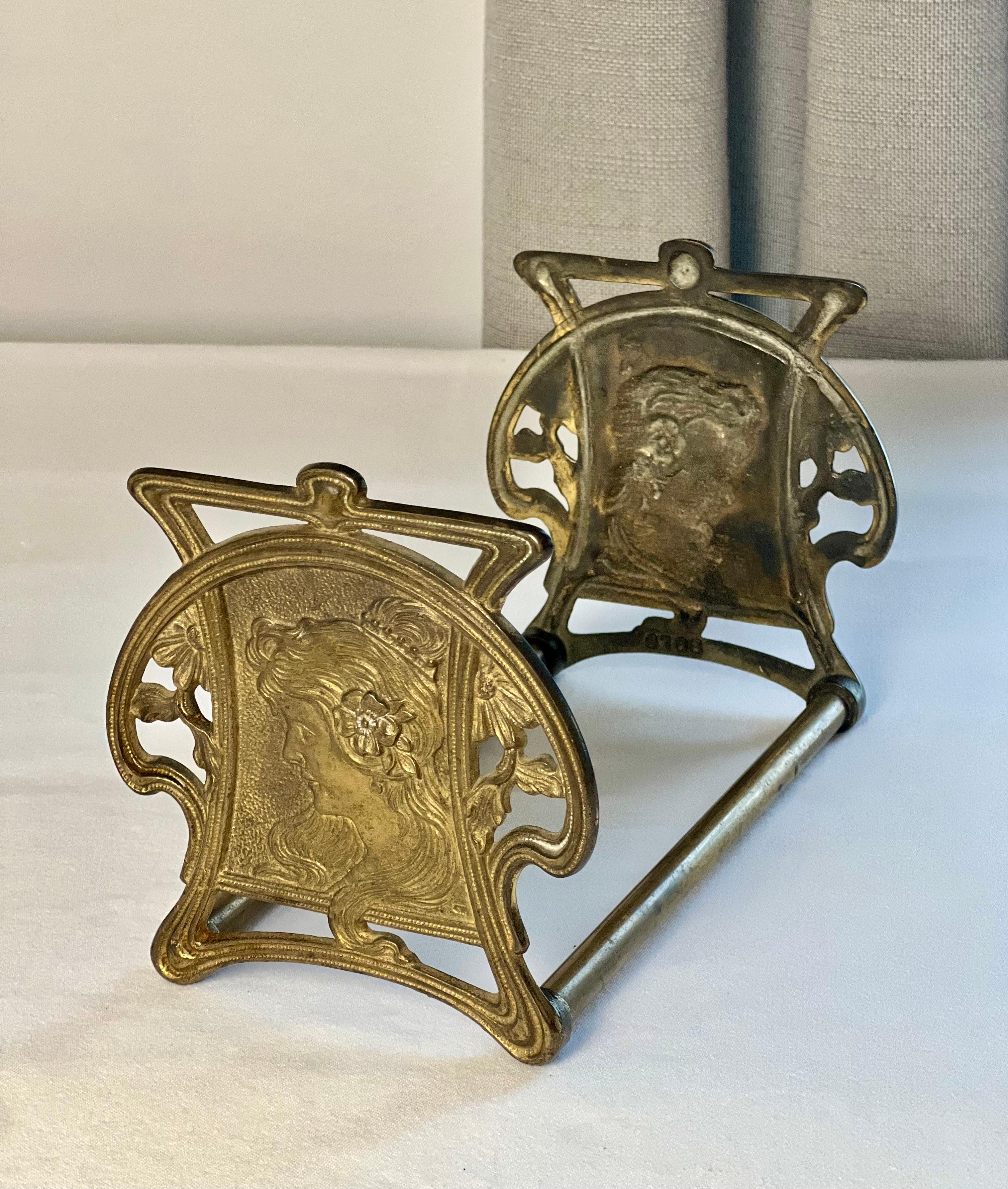 Art Nouveau bronzed cast iron and brass book stand attributed to the Judd Foundry, c. 1920s.

The stand portrays the profile of a pretty Mucha woman in relief with flowing hair and flowers on both ends. It smoothly slides to adjust from 8.5