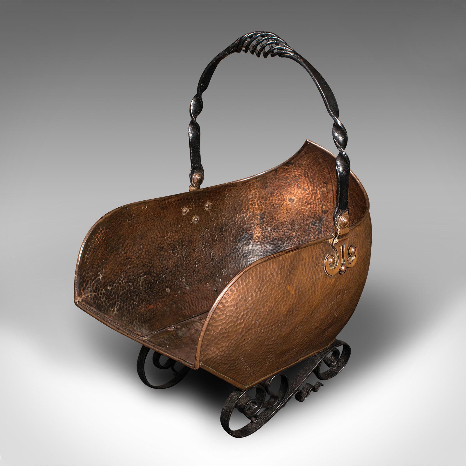 This is an antique Art Nouveau coal scuttle. An English, copper and wrought iron fireside log bucket in the shape of a pram, dating to the late Victorian period, circa 1900.

Fascinating form and wonderful hand-beaten appeal
Displays a desirable