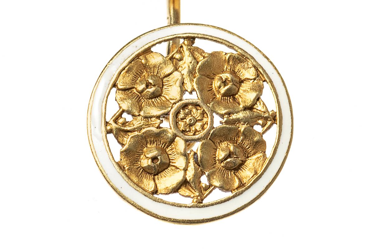 An attractive pair of 18 karat yellow gold, Art Nouveau, double sided circular cufflinks designed with a cluster of four flower heads and leaves surrounded by a border of white enamel. The dividing bar link is stamped 750 for 18 karat gold. In the