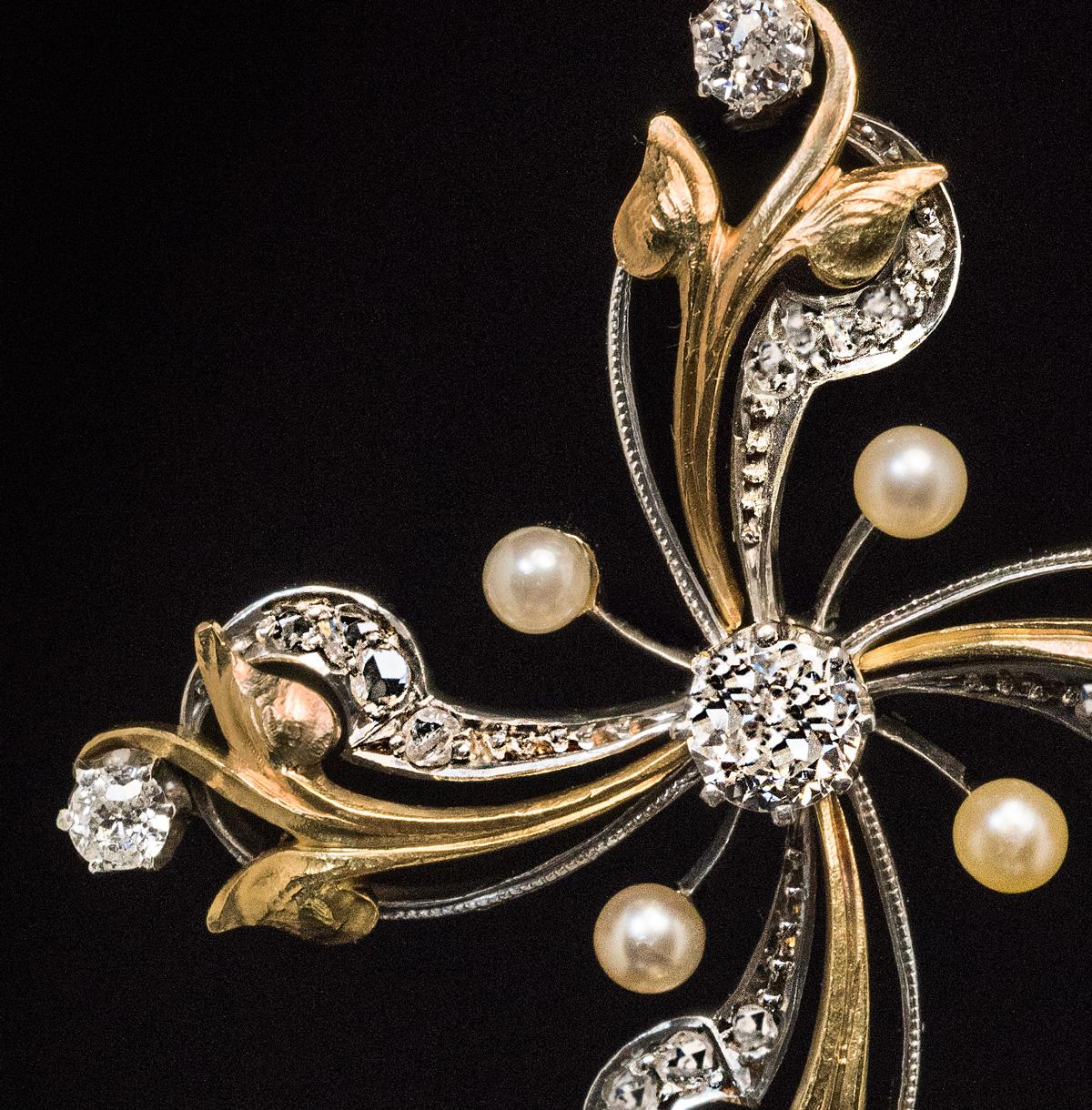 Circa 1900

This ornate Art Nouveau floral-motif cross pendant is certainly one-of-a-kind. The pendant is handcrafted in 14K gold and silver and embellished with six sparkling old European cut diamonds, five seed pearls and numerous small old rose