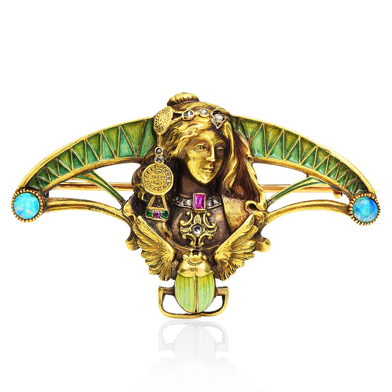 An Antique mythical Egyptian Revival Scarab with a gypsy style lady face design, enhanced by green enamel accents.

This Art Nouveau antique piece has a textured finish and is enhanced on every end by two black opal stones, with a bezel-set, of 3