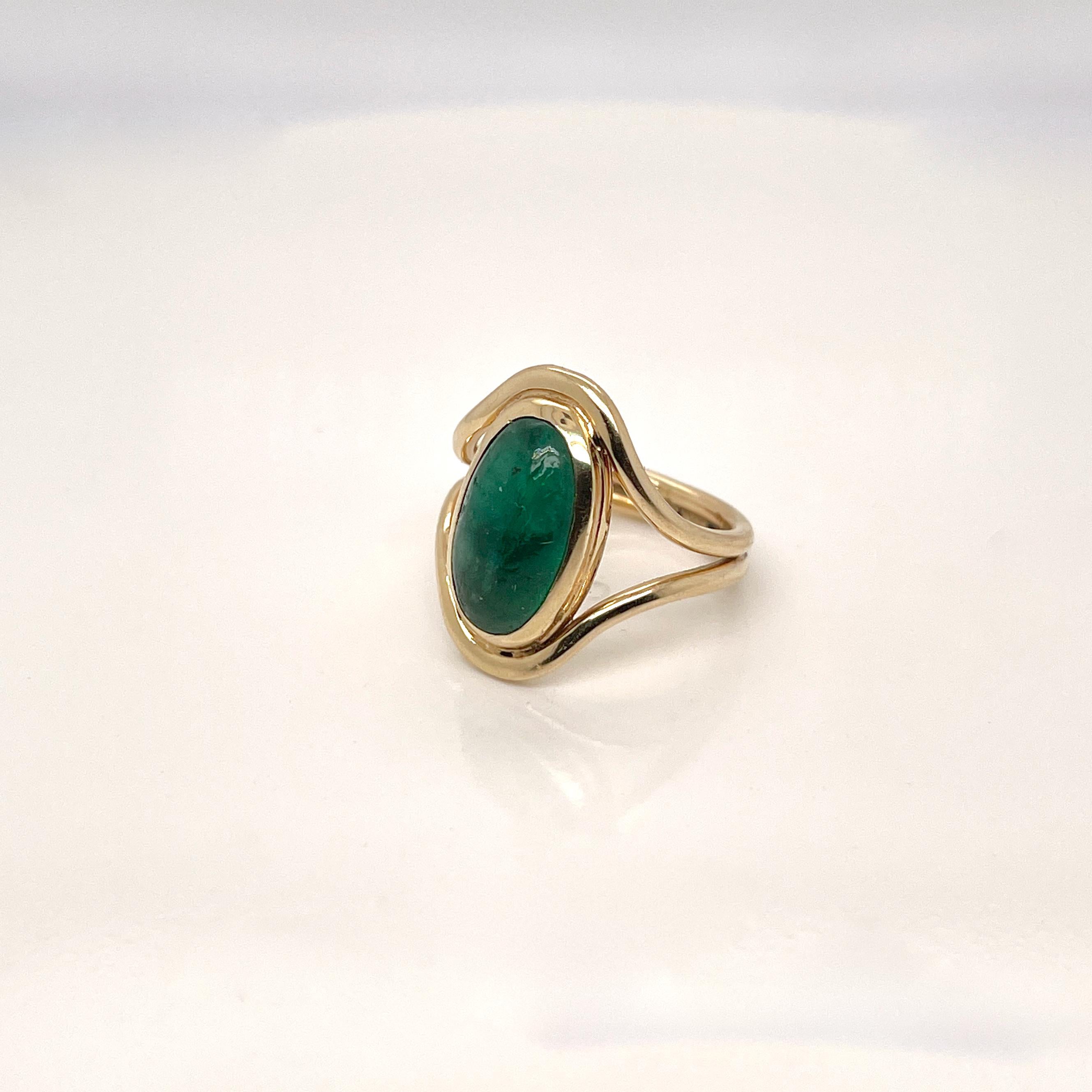 A fine Art Nouveau Signet type ring.

With a smooth oval emerald cabochon bezel set in 14k gold. 

The setting comprised of two gold bands that frame the stone and are conjoined at the bottom.

Simply a stunning emerald signet ring! 

Date:
Early