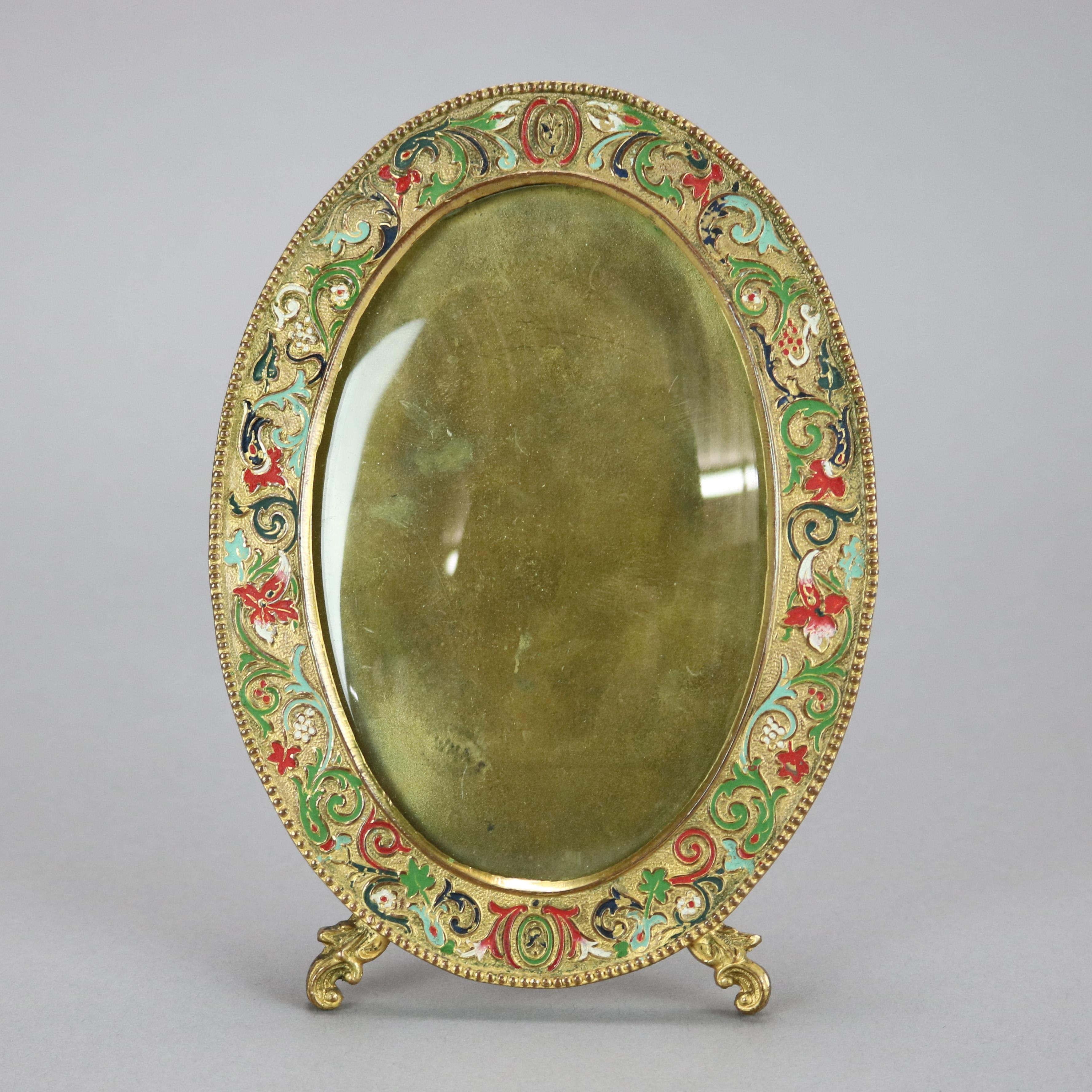 An antique Art Nouveau table top picture frame by AMW (Art Metal Works) offers gold plated exterior with scroll, floral and foliate enameled decoration with bead bordering, c1900

Measures - 7.25''H x 5.25''W x .5''D.