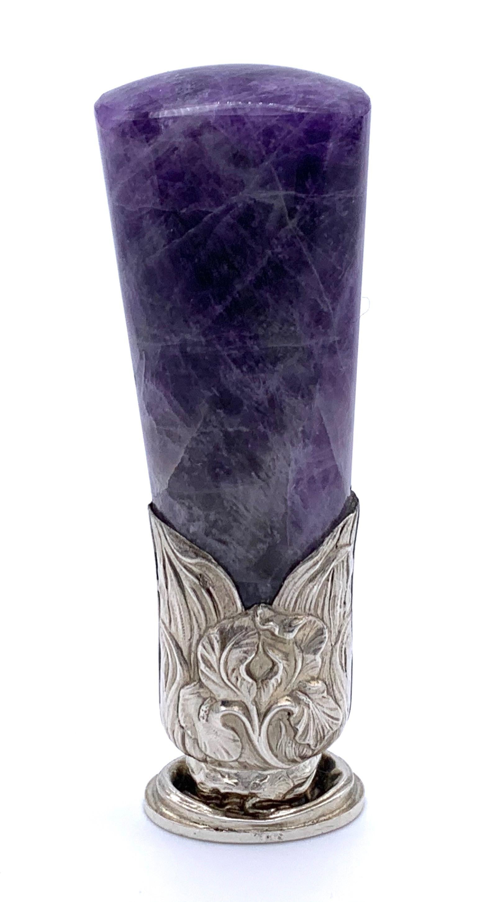 This unusual silver French desk top seal with a chunky violet fluorite handle has been handcrafted in 1895 ca. The fluorite fluorspar is set in a silver mount and decorated with iris and leaves. The oval seal bears the initials E M J under a small