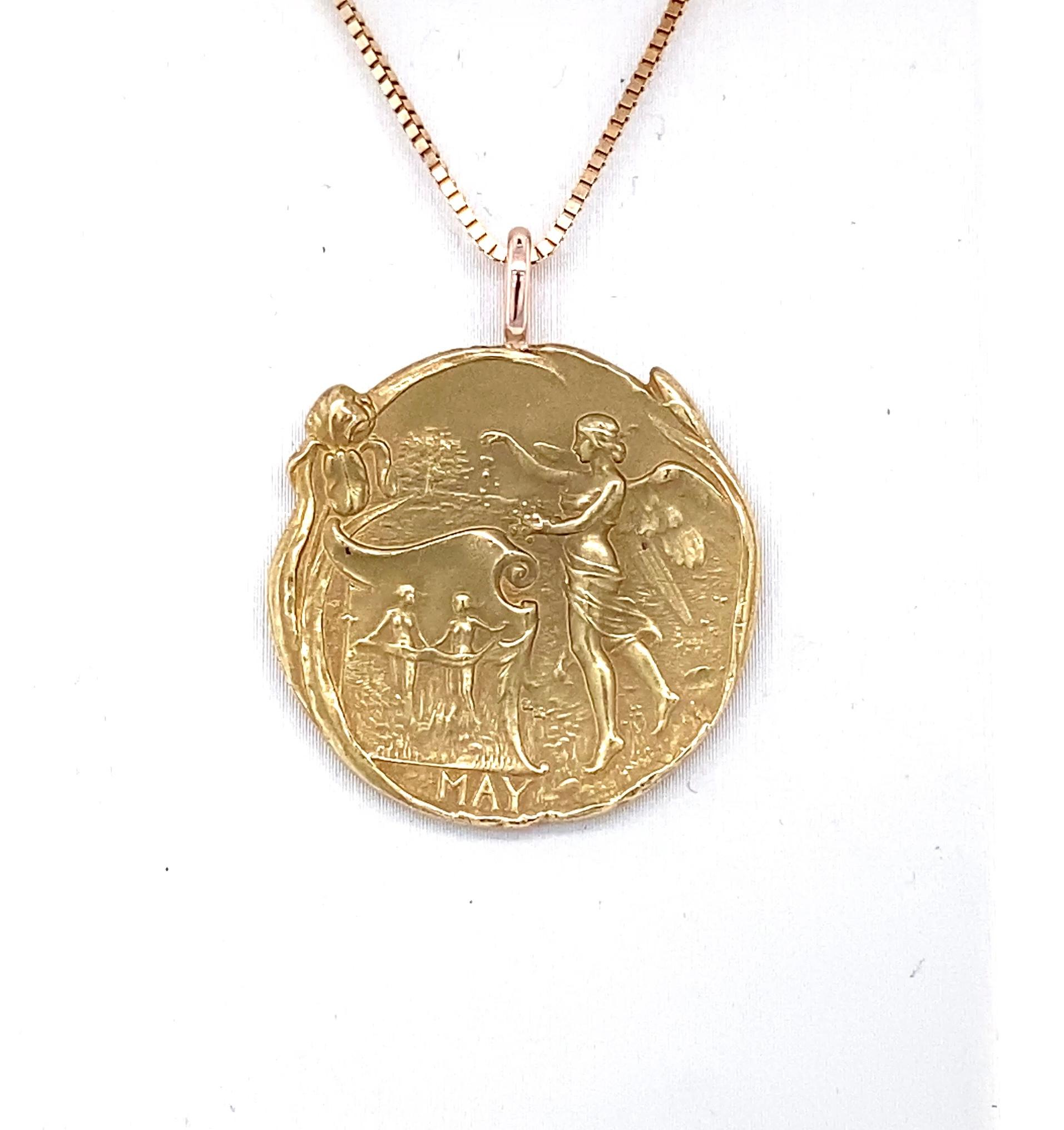 Finemente dettagliato, questo ciondolo in stile Art Nouveau raffigura la dea greca Maia.  Con le sue ninfe sullo sfondo, Maia semina semi che riflettono il suo legame con la primavera e la crescita. Il contorno irregolare della medaglia in oro