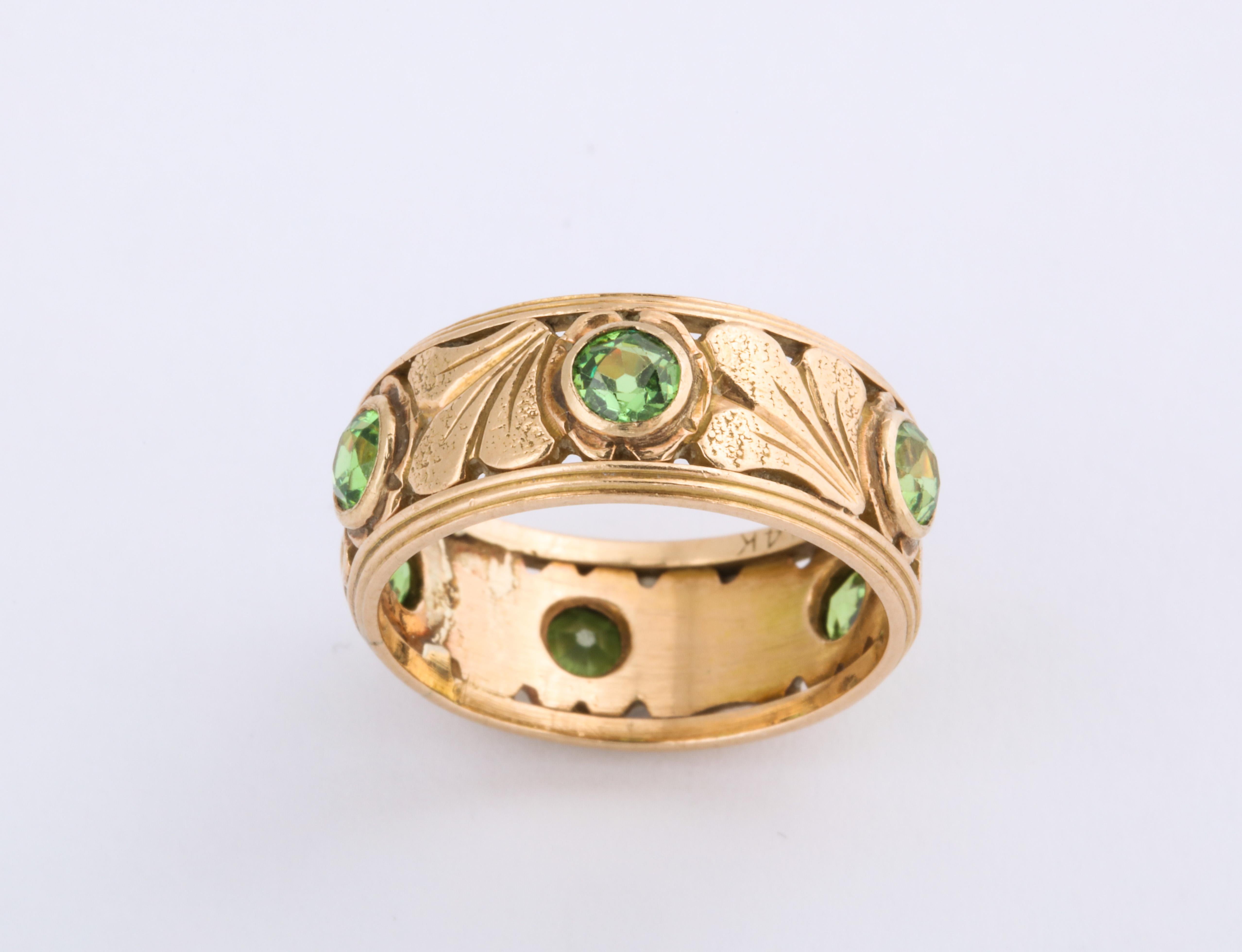 For the love of beauty, six rare, green, demantoid garnets, brilliant cut, bring bright, unique color to this ring of 14 Kt gold made in the Art Nouveau era, c. 1910. The demantoids total weight is approximately 3.89-3.90 cts. The green garnet is