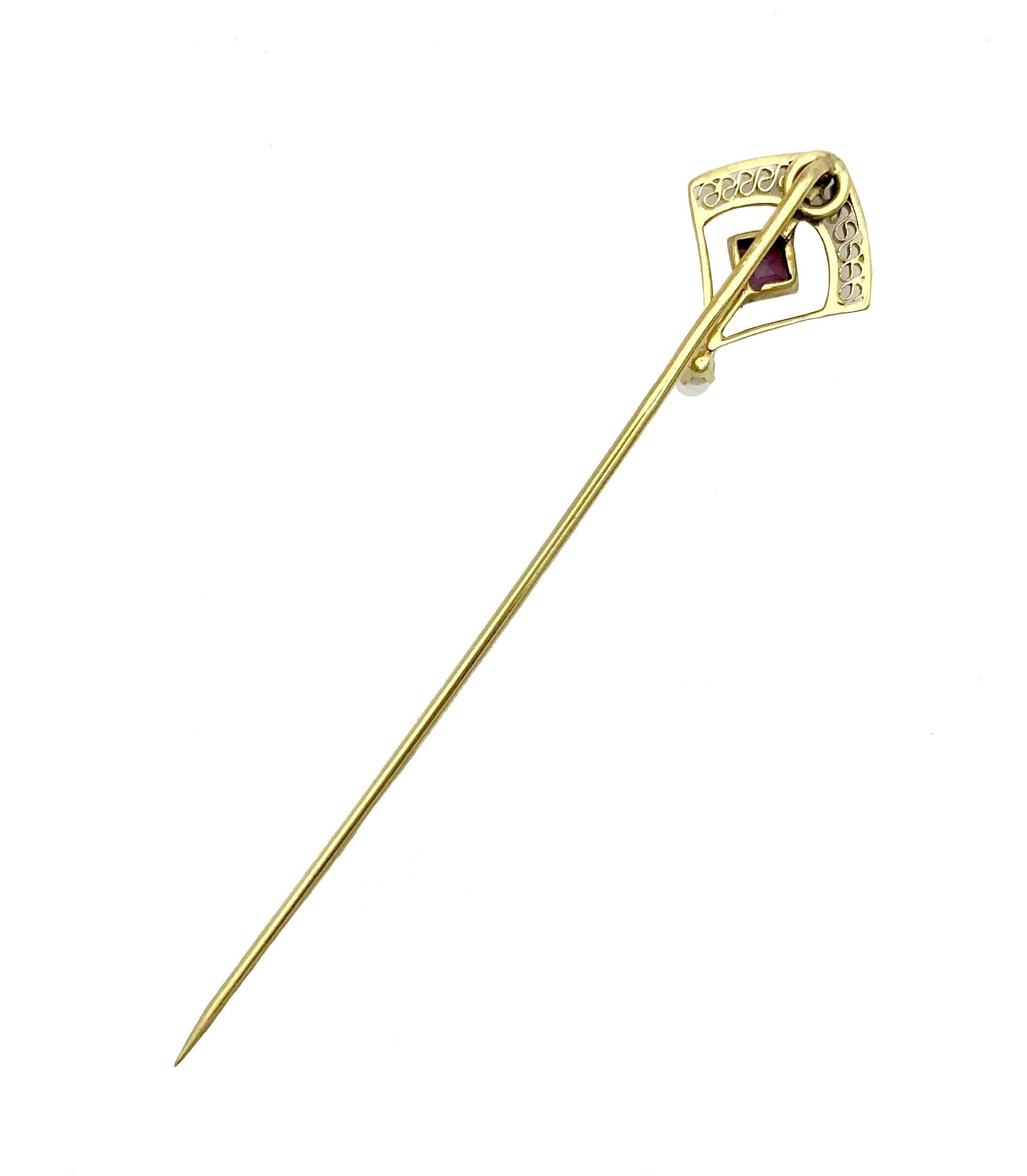 This elegant  Art Nouveau stickpin was created out of 10K gold around 1900. The head of the pin is designed in the shape of a kite and decorated with a meandering ornament made out of a strip of gold. A square cut amethyst and a half pearl. 