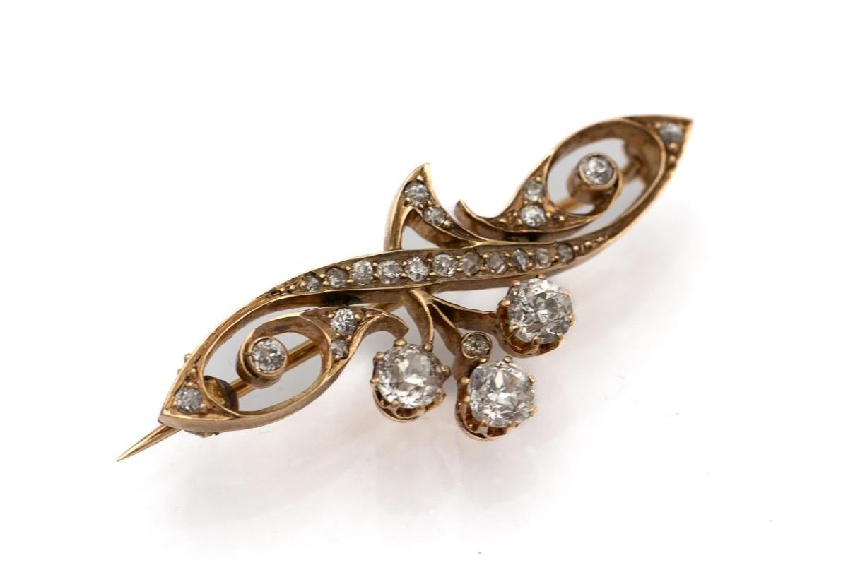 Antique brooch made of yellow 14-carat gold (0.550 fineness) with diamonds.

A delicate openwork form of a brooch in a characteristic Art Nouveau style, referring to curved lines inspired by nature.

Decorated with three unusual diamonds at the