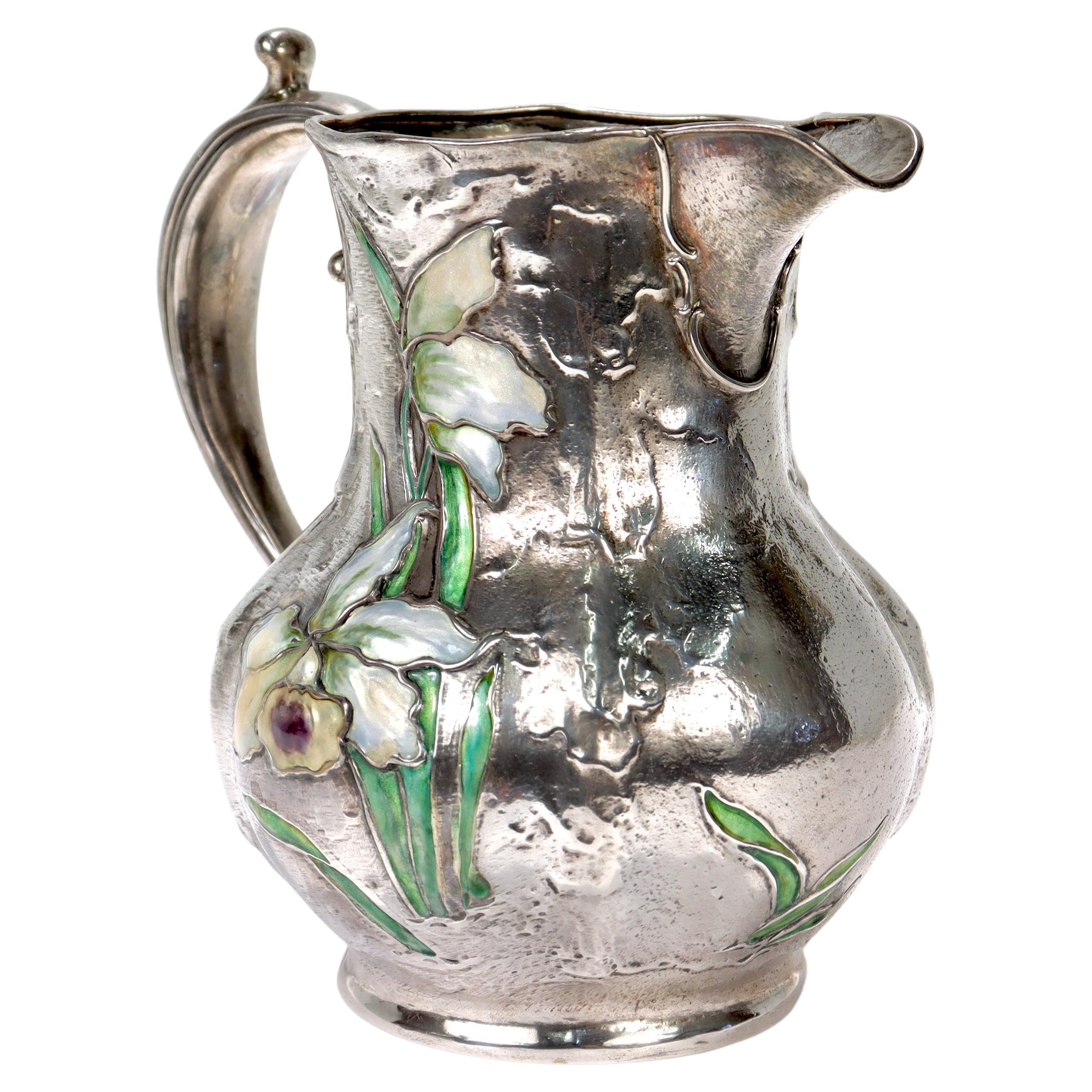 An extremely rare, antique Art Nouveau sterling silver & enamel pitcher.

By Gorham.

With a hand-hammered body having floral decoration to both sides. 

The front side is decorated with polychrome enamels.

Gorham produced a very limited series of