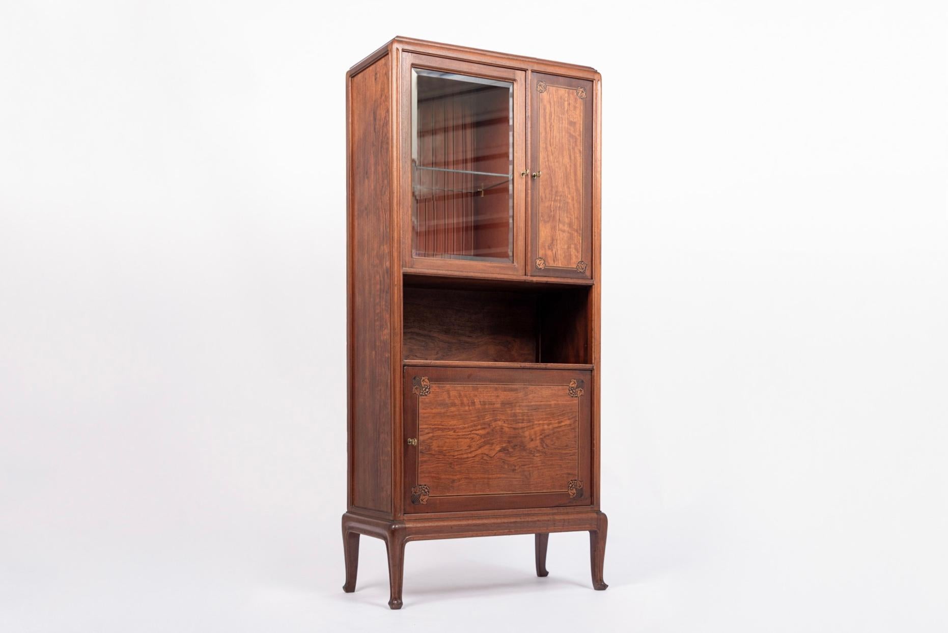 This exquisite antique French Art Nouveau inlaid wood and glass cabinet was designed by Louis Majorelle and made in Nancy, France circa 1910-1920. This exceptional, museum quality cabinet exemplifies elegant, Art Nouveau design featuring sinuous,