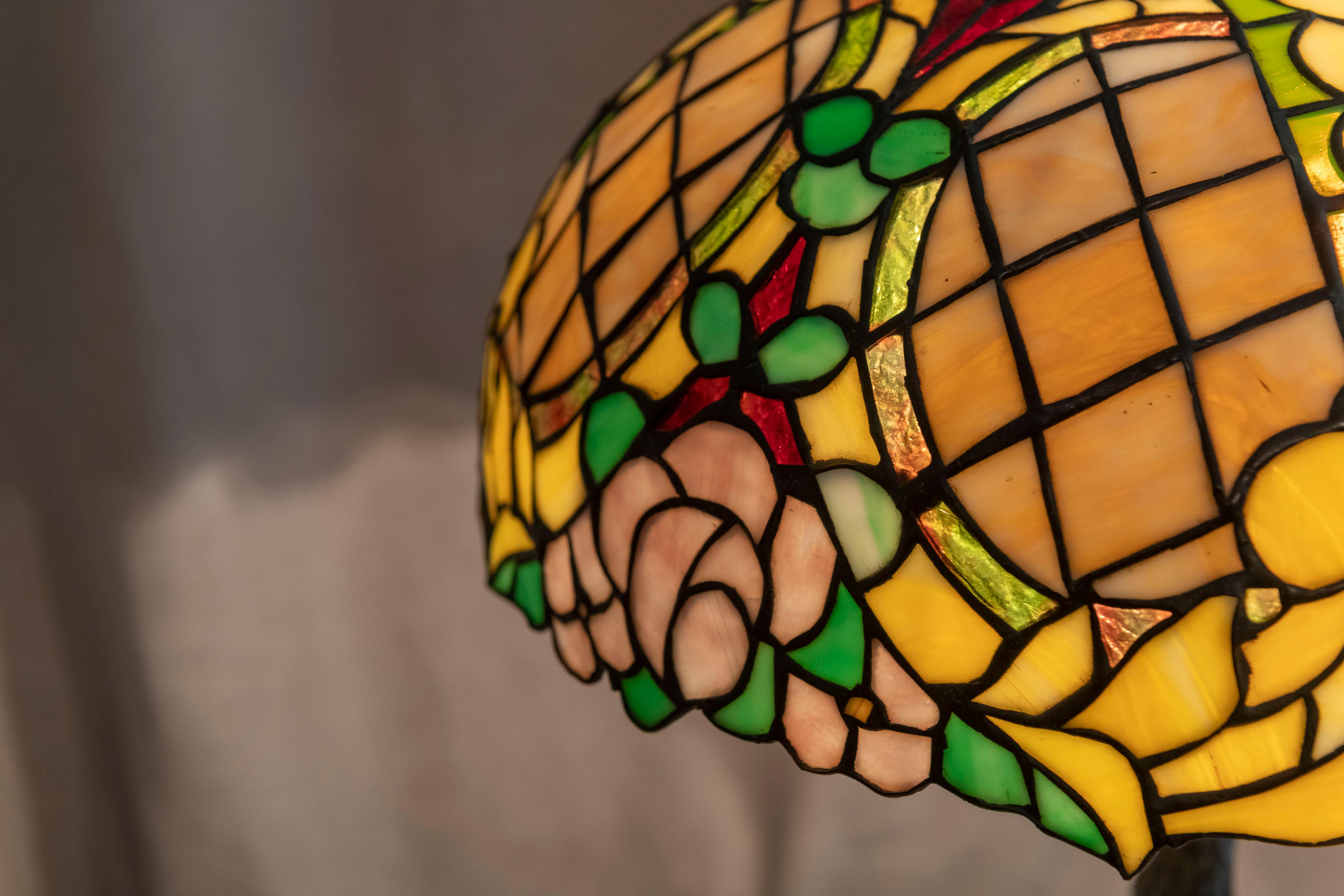 Cette lampe de table en verre plombé à motifs floraux très colorés a été fabriquée par la Chicago Mosaic Lamp Co. La lampe est totalement originale, y compris l'embout, le capuchon thermique, la base et bien sûr l'abat-jour. Bien qu'elle ne soit pas