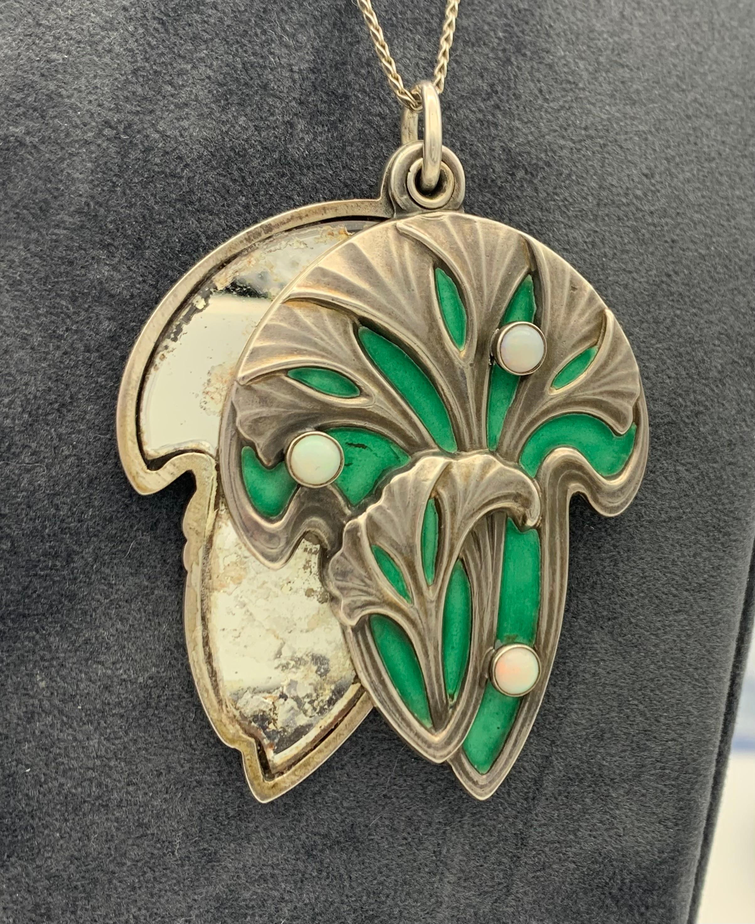 This fine size pendant is decorated with gingko leaves in relief standing out against a green enamelled background. slides open to reveal a mirror. The reverse is marked 900 and impressed with a dragon fly, the Meyle &Mayer's company's signature.