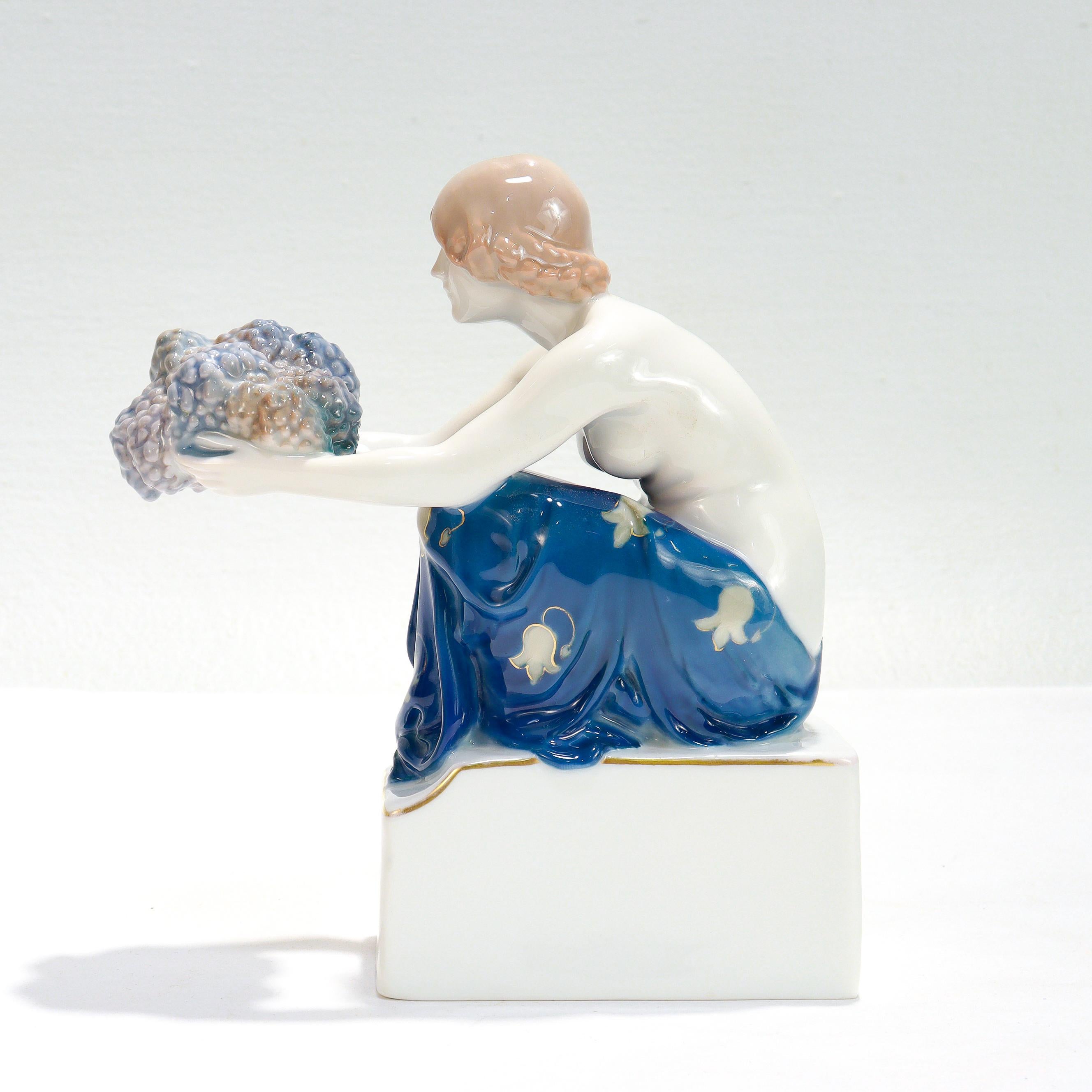 Fina estatuilla antigua alemana de estilo Art Nouveau.

Titulado el Portador de la Uva:

Por Rudolf Marcuse para Porcelana Rosenthal.

Model No. 477.

Representación de una joven semidesnuda sentada sobre un pedestal, con racimos de uvas en los