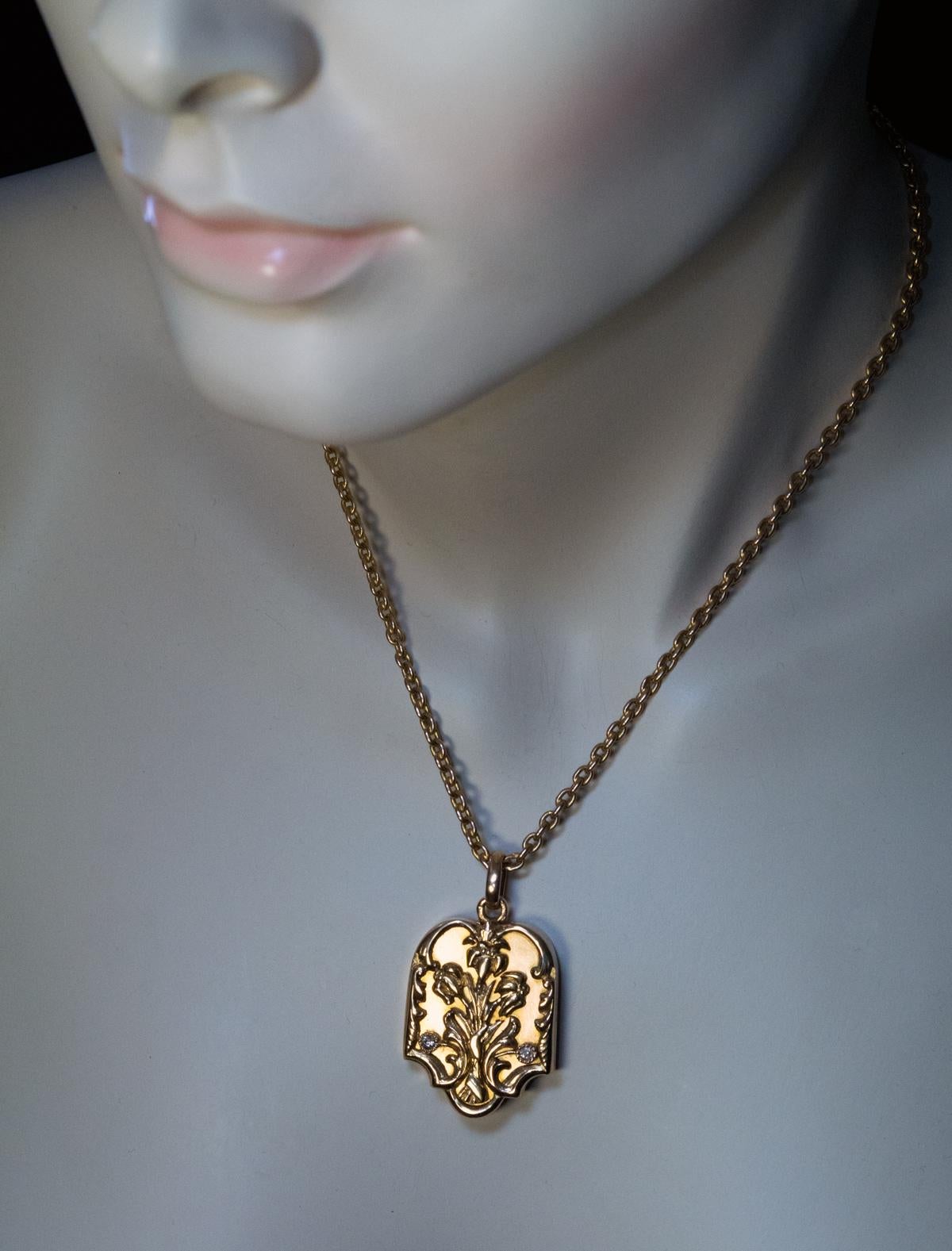This Tsar Nicholas II era antique Russian gold locket pendant was made in St. Petersburg between 1908 and 1917. The matte cover  is applied with a spray of shiny Art Nouveau style flowers accented by two diamonds and framed by chased foliage.

The