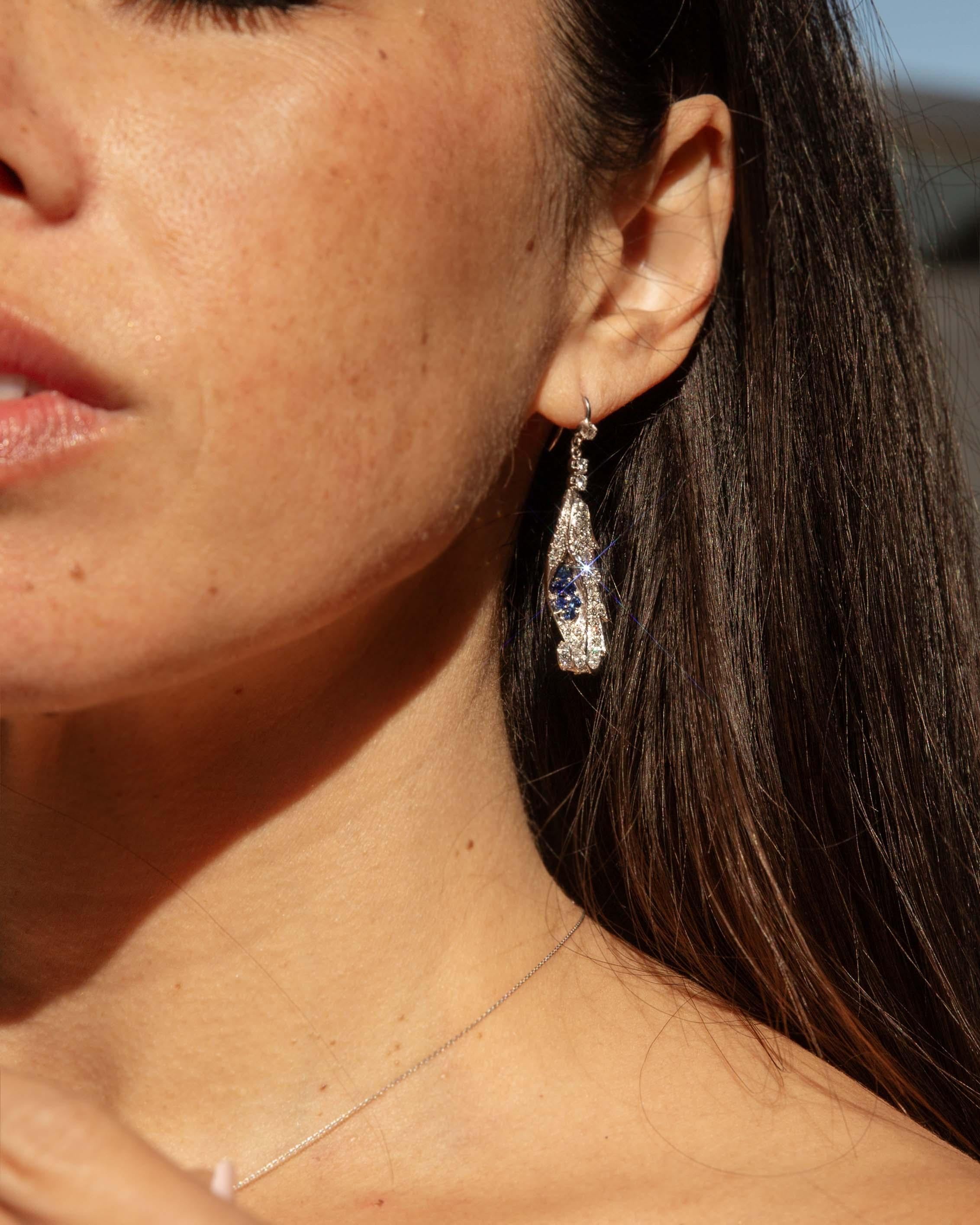 Irradia eleganza con gli affascinanti orecchini Camile con zaffiro e diamante, realizzati in oro bianco 18 carati. Questi squisiti tesori, impreziositi da zaffiri brillanti e diamanti scintillanti, riecheggiano la raffinatezza di un'epoca passata.