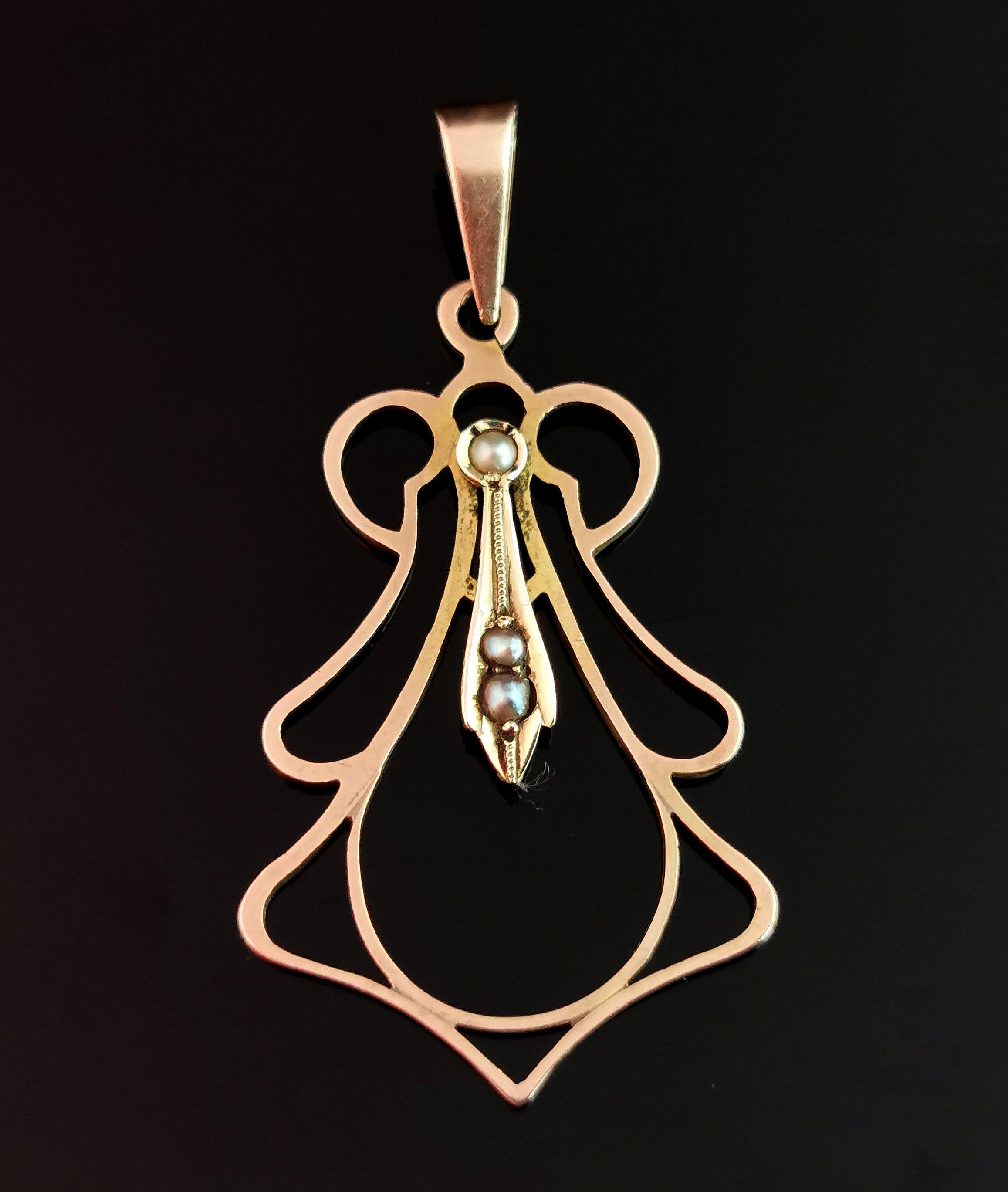 A beautiful antique, Art Nouveau era seed pearl pendant in 9k gold. 

The pendant is a kite or teardrop shape, openwork with scrolling and curved accents.

To the centre the pendant is set with three tiny creamy seed pearl and it has an integral