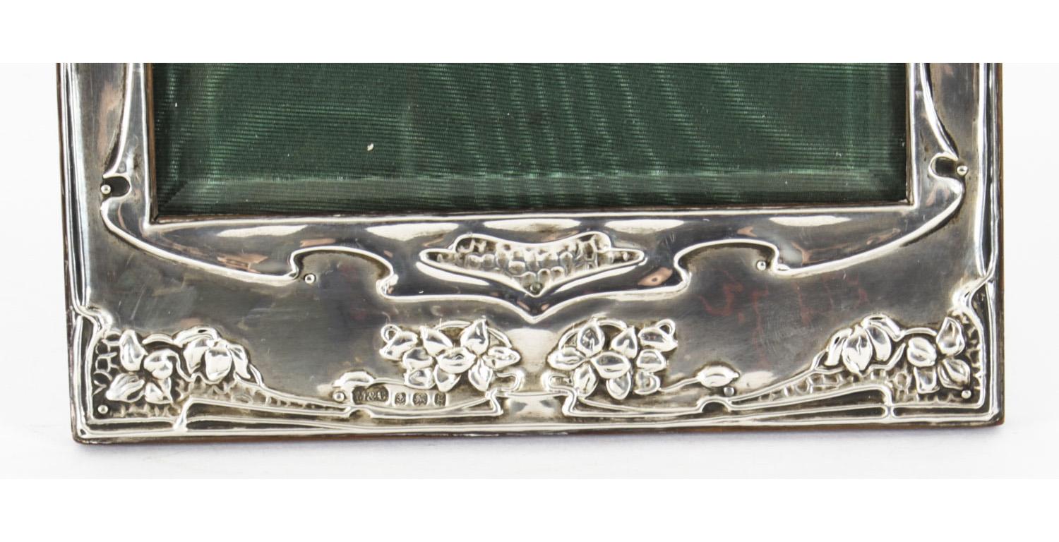 An elegant antique Art Nouveau sterling silver photograph frame with hallmarks Marks & Cohen (Walter Henry Marks & Samuel Tobias Cohen), Birmingham, 1906

The frame features sylized embossed flowers and a polished oak easel back.

An excellent gift