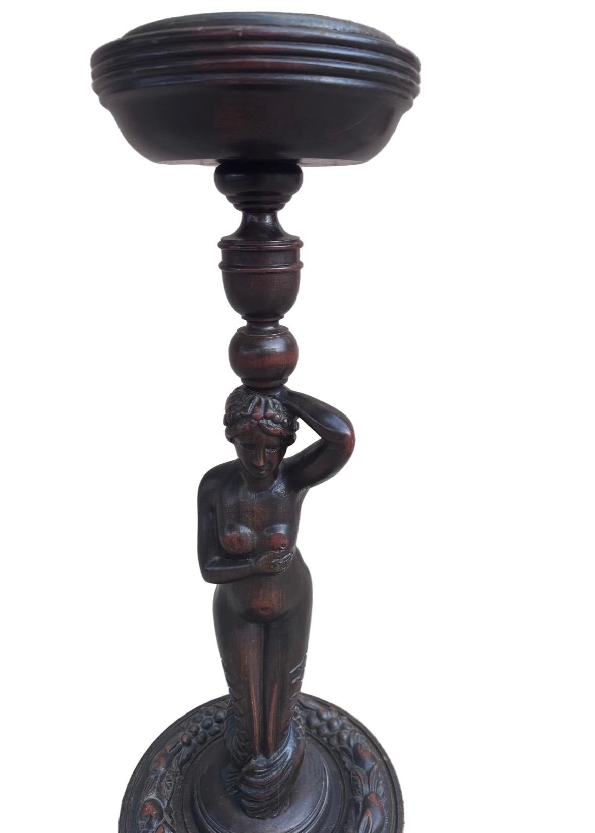 Cet exquis cendrier de sol du début du XXe siècle présente une captivante figure de sirène magistralement sculptée dans un riche acajou, dans le style fluide et organique de l'Art nouveau. La forme sculpturale et élégante met en valeur le mouvement,