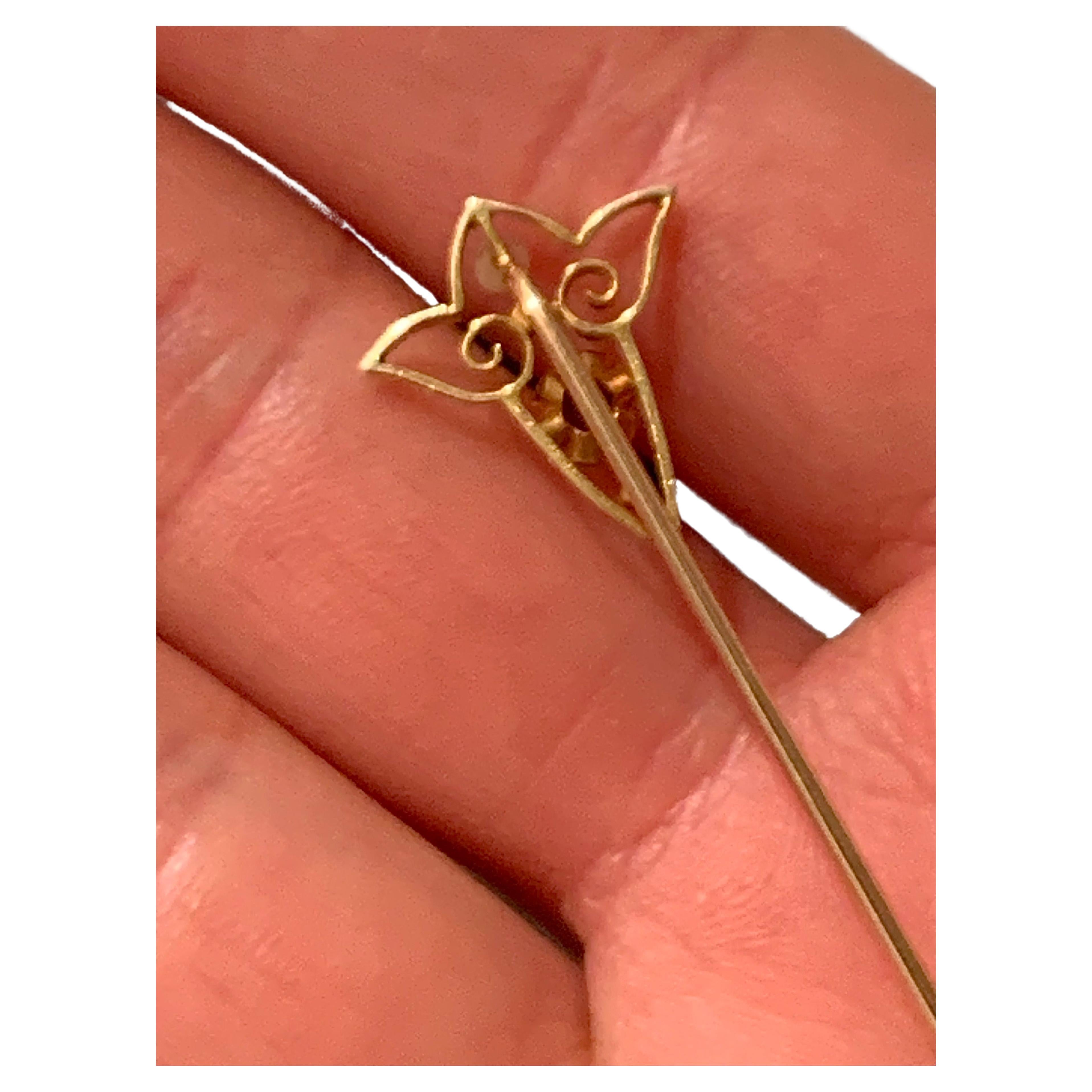 This elegant Art Nouveau tie pin has been handcrafted out of 14 karat yellow gold. The strong and typical Art Nouveau line has been translated into a creation which uses  a wide gold ribbon to express a powerful Art Nouveau Design. A bright blue