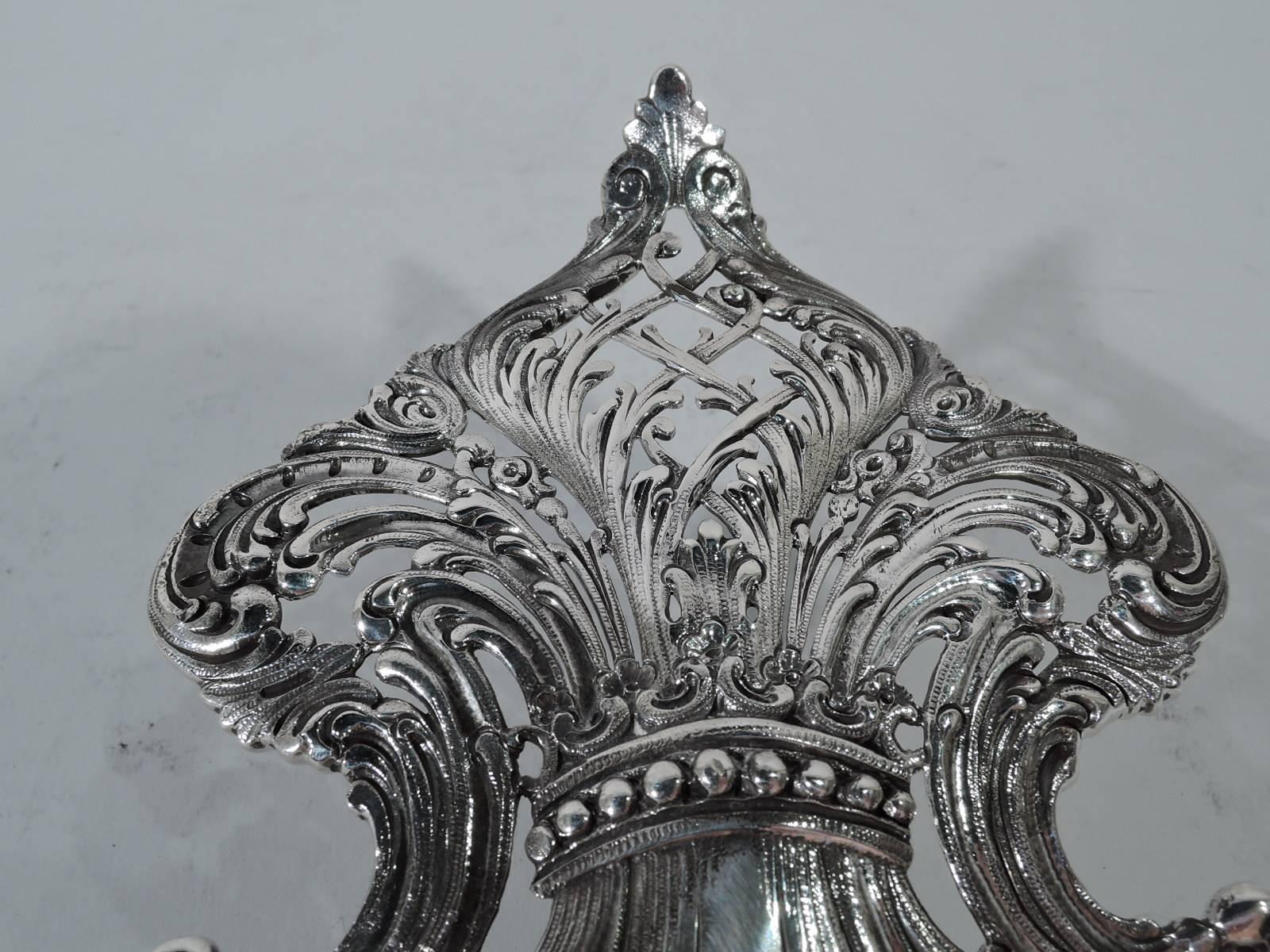 Very beautiful sterling silver petit four plate. Made by renowned Tiffany & Co. in New York, circa 1892. Ovoid fan with soft ribbing and scrolled frames with alternating flowers and pierced diaper. Regal fleur de lys handle with large scrolled frame