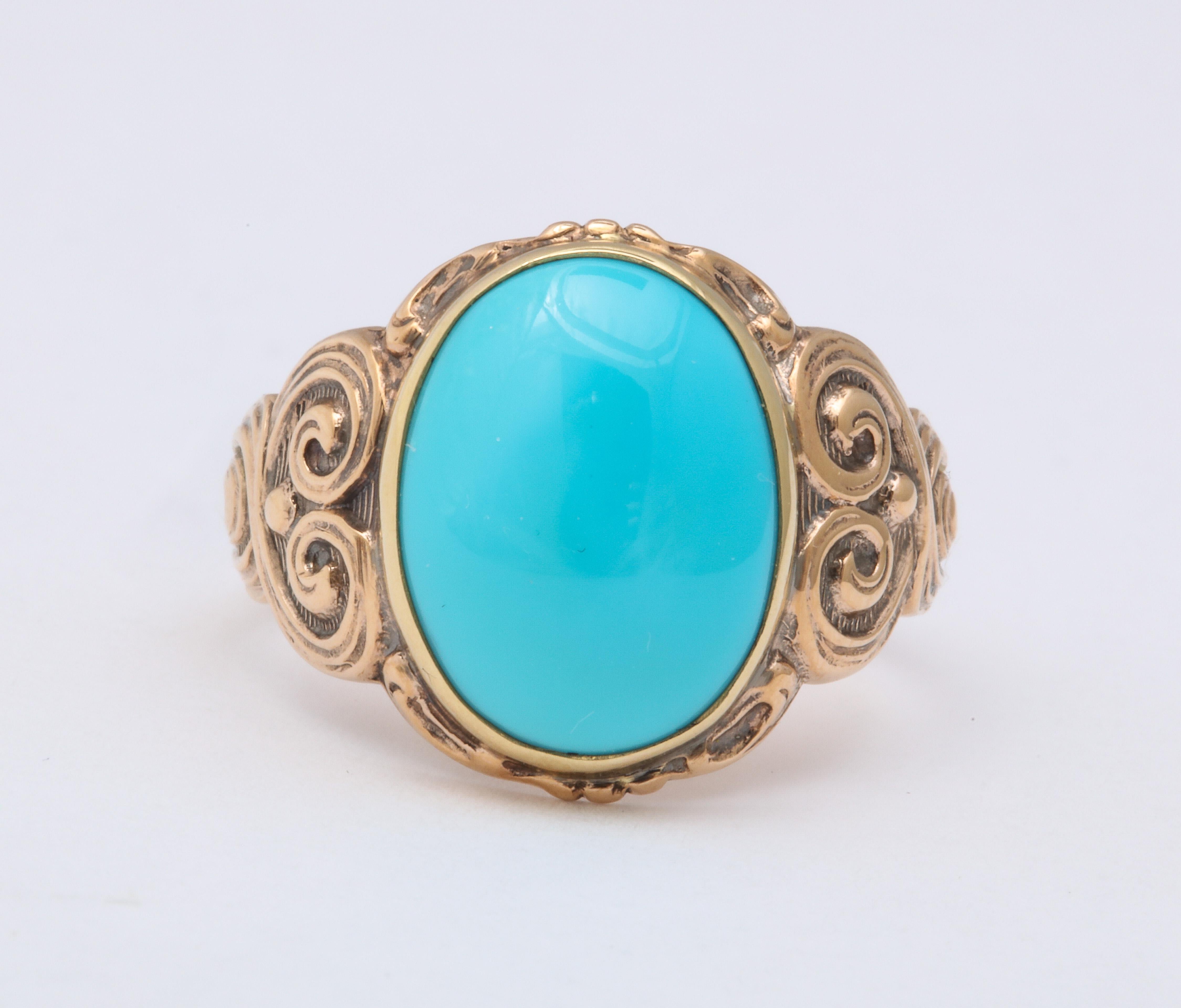A 5.5 ct oval turquoise ring is cut in cabochon and set in a 14 kt engraved shank. The shank tapers from its repousse swirls on the shoulders. The ring is all original. The engraving travels half way around the finger. The collet keeps the turquoise