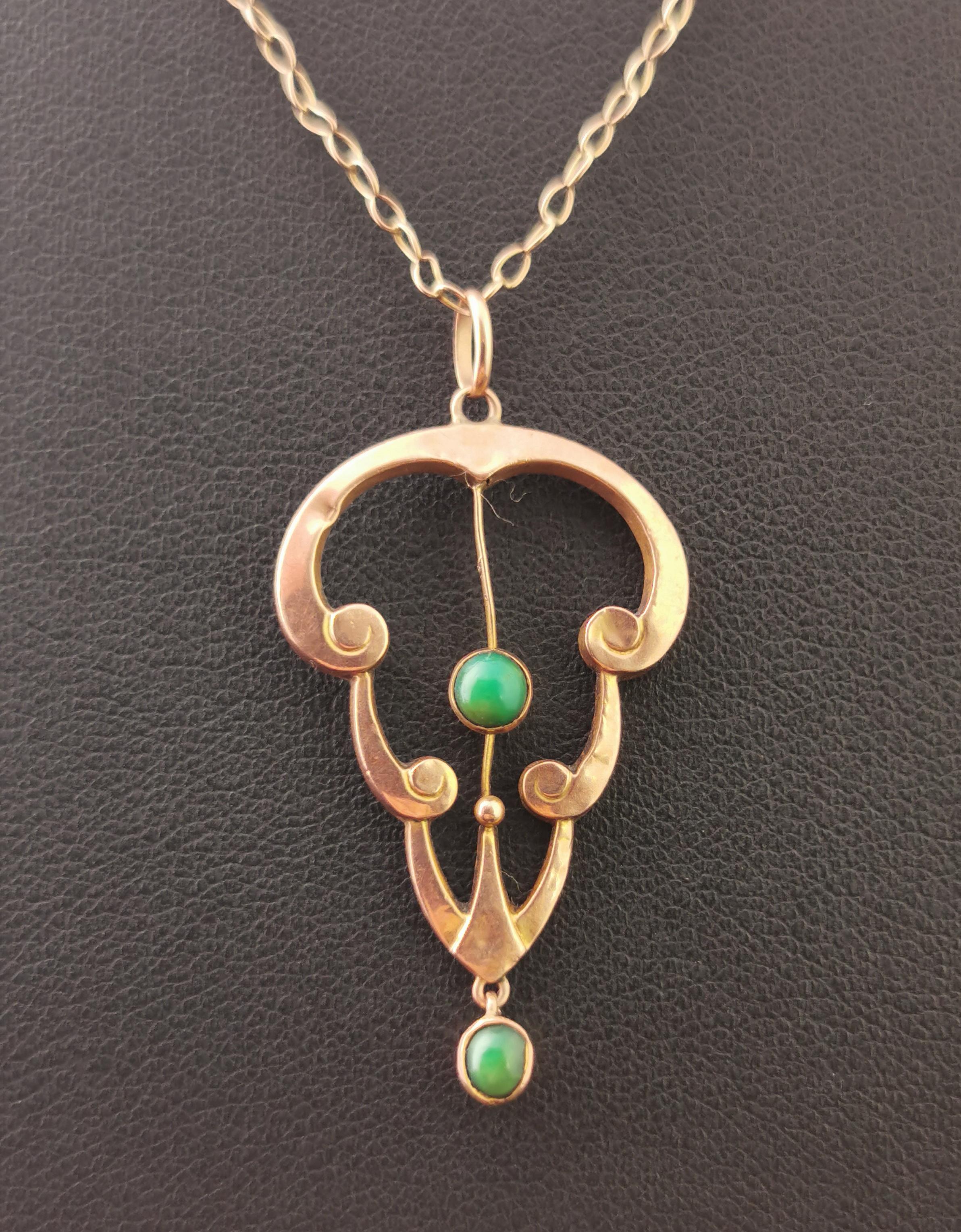 A sweet little antique, Art Nouveau era turquoise lavalier pendant.

Scrolling arches of rose gold with a vivid green turquoise cabochon set in the centre.

The bottom of the pendant has a small articulated drop set with a further turquoise