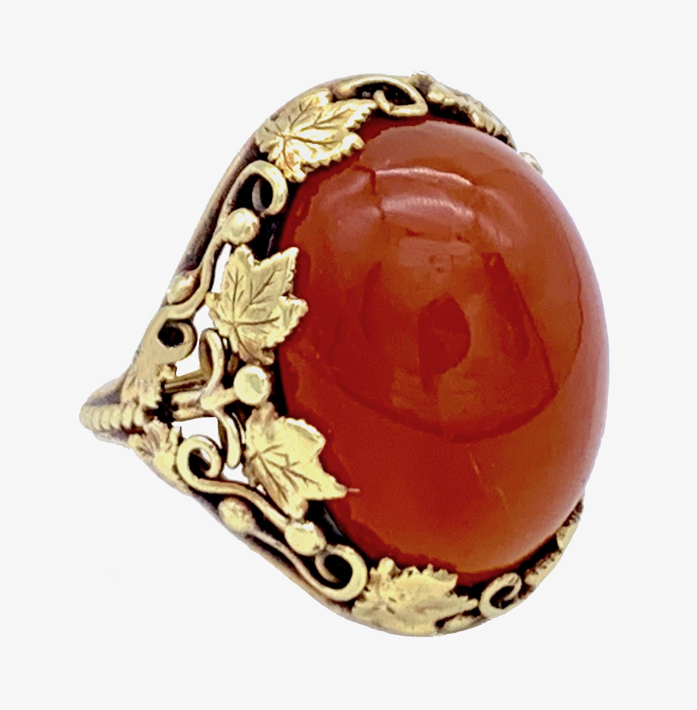 This elegant Art Nouveau Ring has an oval carnelian cabochon mounted in a setting made out of vine and vine  leaves handcrafted out of 14 karat gold in 1900ca. The shank is decorated with twisted goldwire.