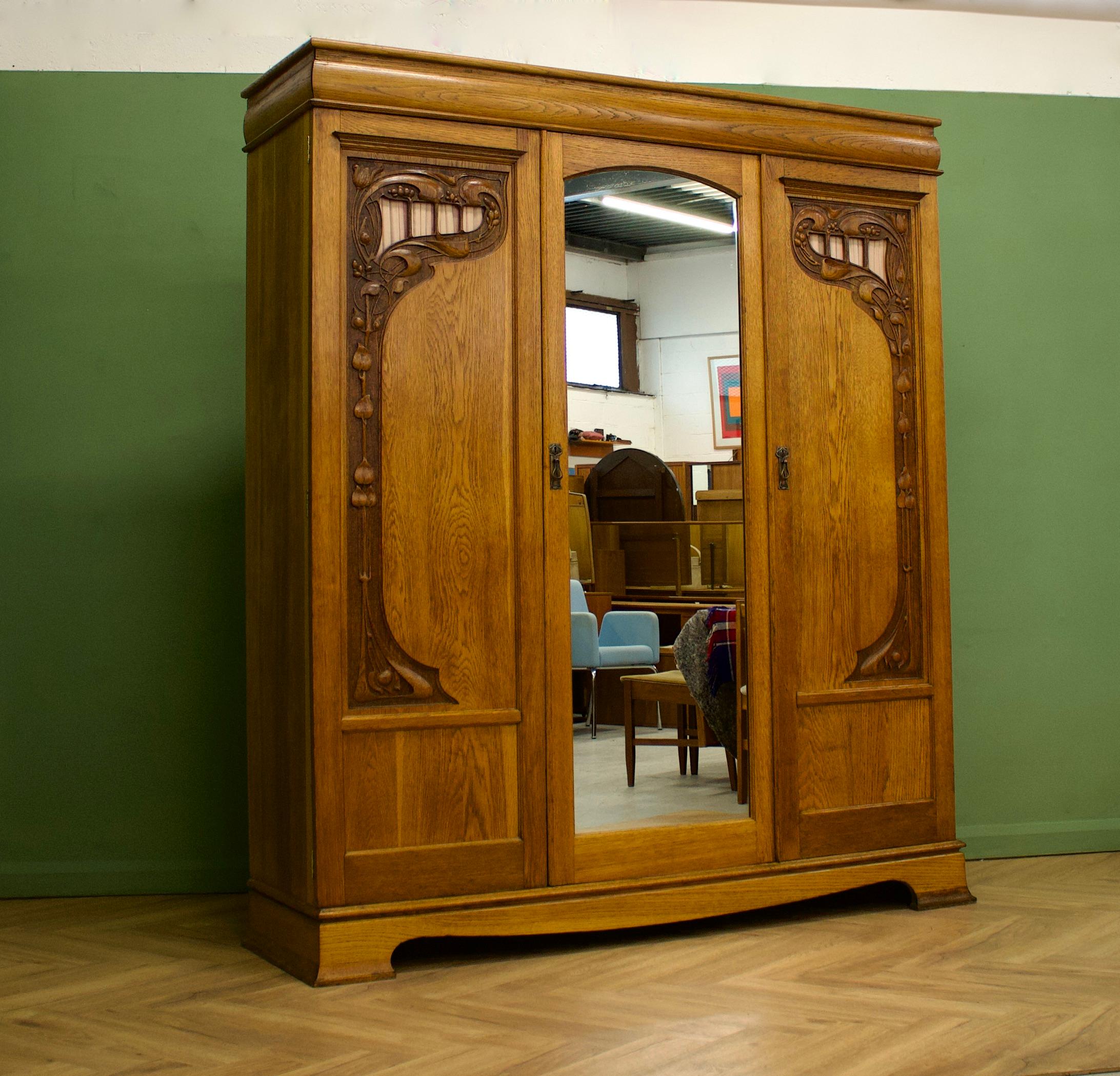 An impressive quality solid oak Art Nouveau wardrobe - circa 1900's


Inside the cupboard has a rail and drawers


There are beautiful hand carved details to each side panel and a full length mirror to the centre door


The wardrobe separates into