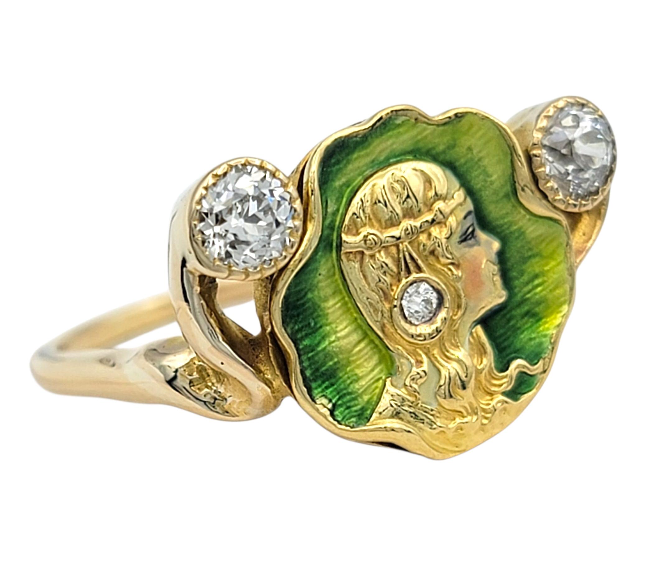 Tamaño del anillo: 6,5

Este anillo Art Nouveau de oro amarillo de 14 quilates presenta en su centro un retrato finamente esmaltado, enmarcado en un vivo fondo verde. El detallado perfil está acentuado con dos diamantes de talla europea antigua a