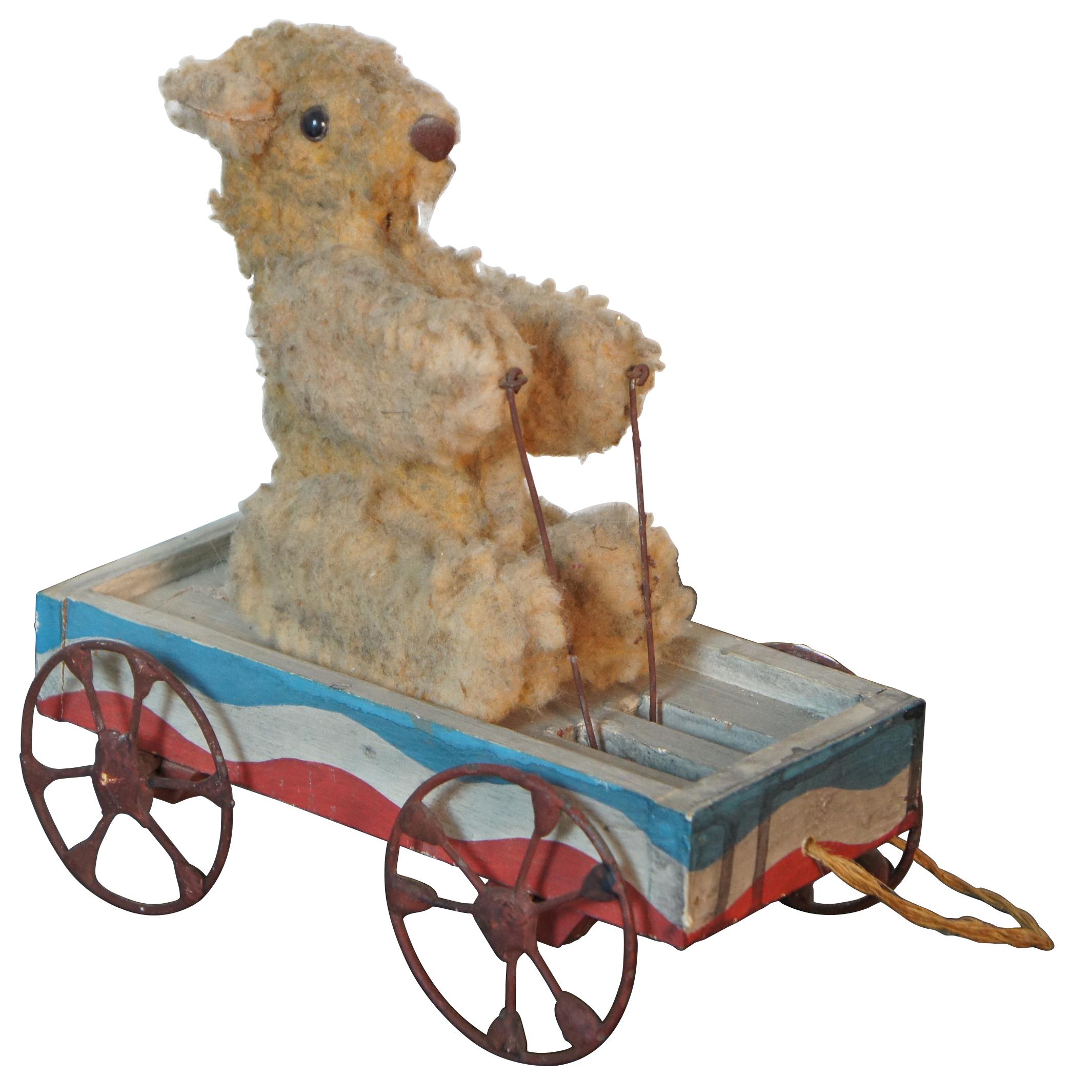 Jouet à tirer antique à plateforme roulante articulée représentant un ours en peluche assis dans un wagon rouge blanc et bleu dont les bras montent et descendent au fur et à mesure qu'il roule.
 