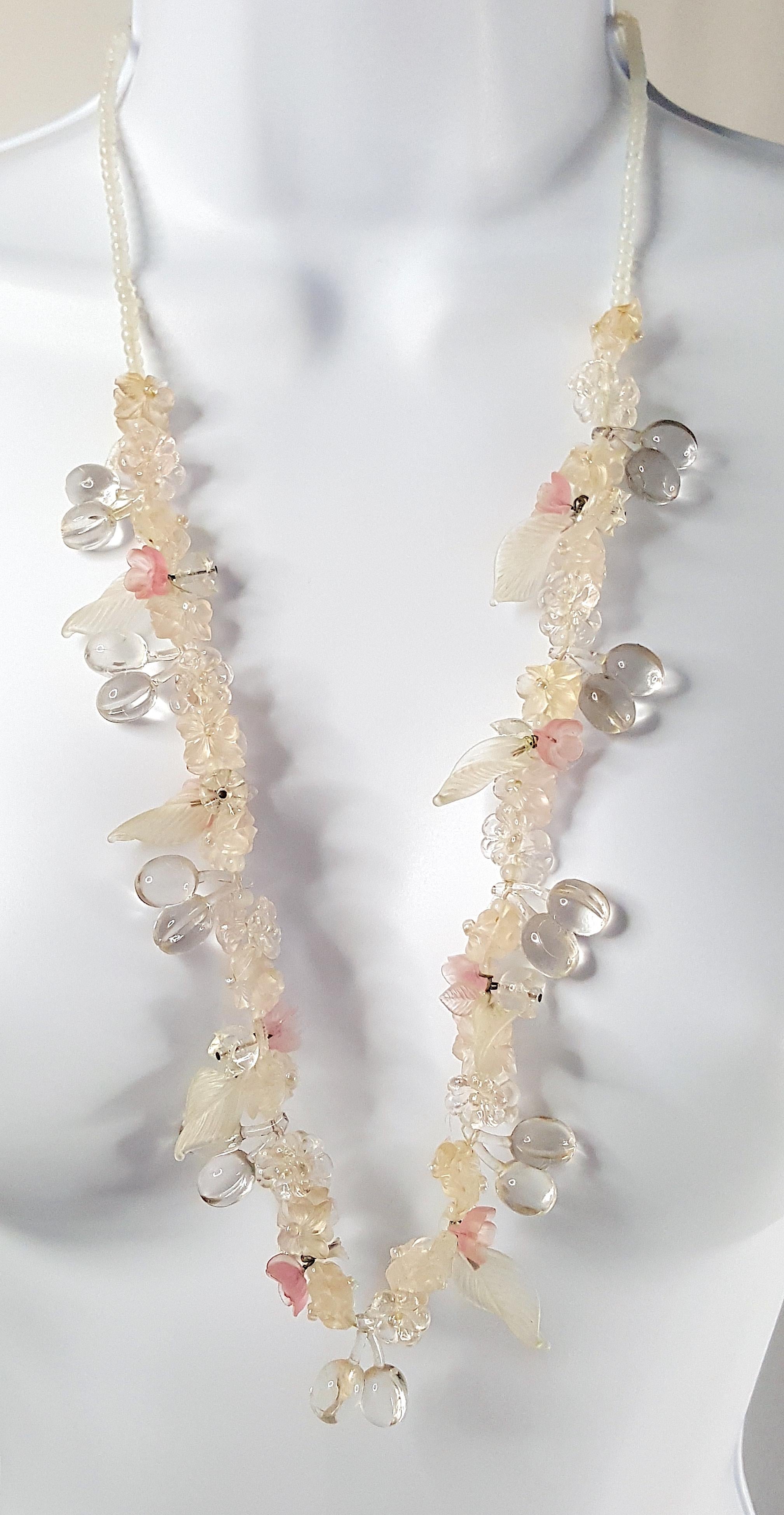 With a silver clasp that could be as old as the Victorian period and in an Art-Nouveau style with pale intricate flora motifs, this antique long glass necklace features lampwork-like hand-pressed glass that realizes pink, frosted and clear flowers,