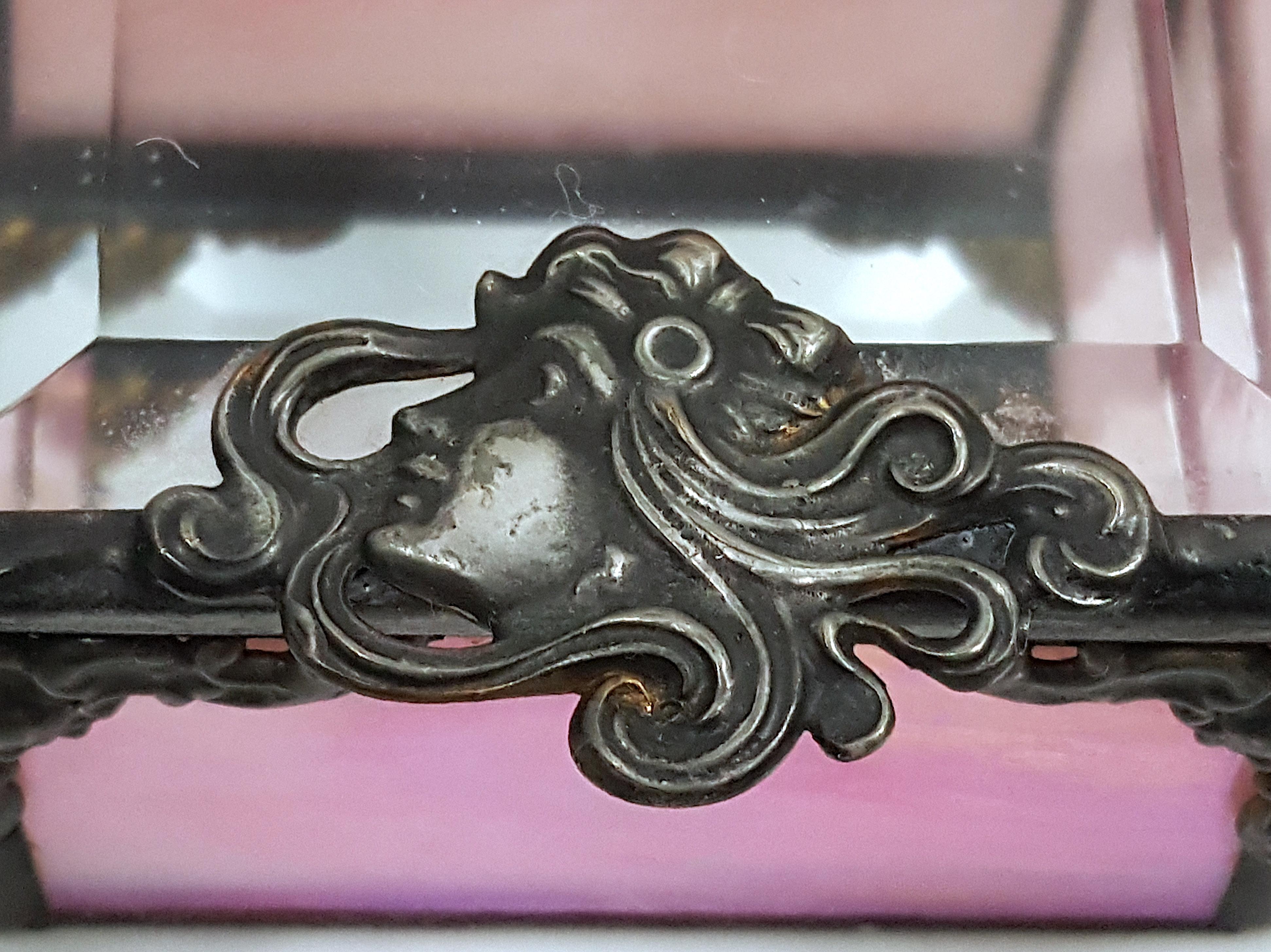 Influencée par les illustrations Art-Nouveau d'Alphonse Mucha, cette ancienne boîte à bijoux française est décorée de plaques en bas-relief en bronze argenté ou en laiton, dominées par la tête courbée d'une dame profilée dont les cheveux