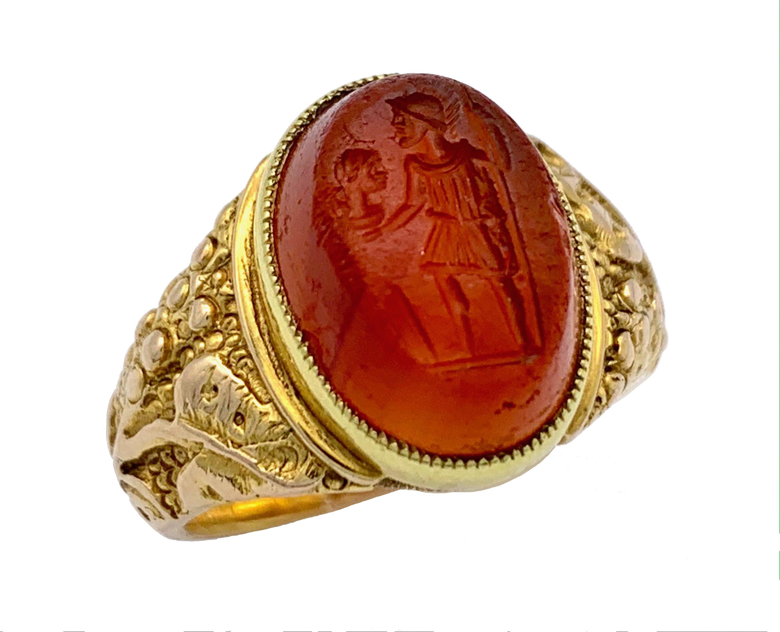 This gem depicts a warrior with helmet and spear, a shield and a head.  The intaglio is carved into a rather high oval carnelian. The mount is made out of 9 karat gold and impressed with 395, the letter p as well as the lions head for London. 